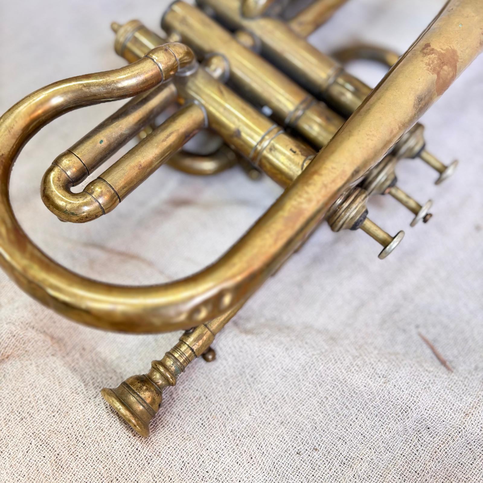 Close-up of a brass cornet on a textured fabric background