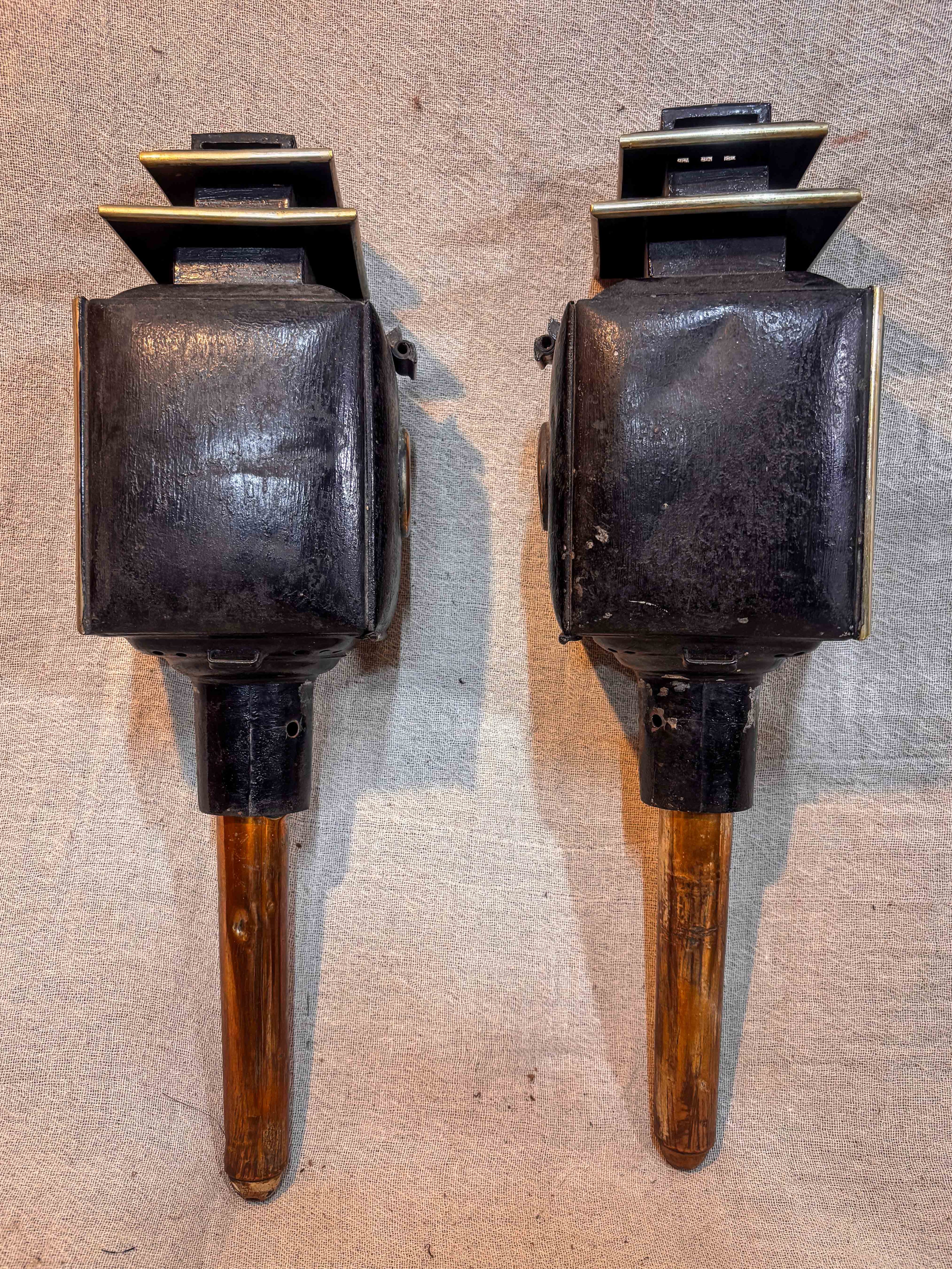 Rear of Two antique carriage lanterns on a textured surface