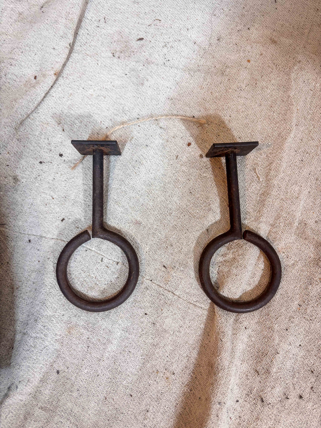 Two rusted metal hooks on a textured stone surface