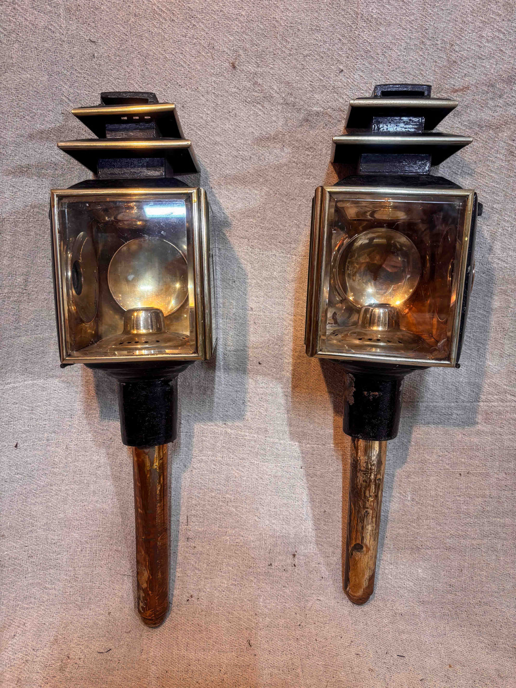pair of antique carriage lamps on a textured surface.