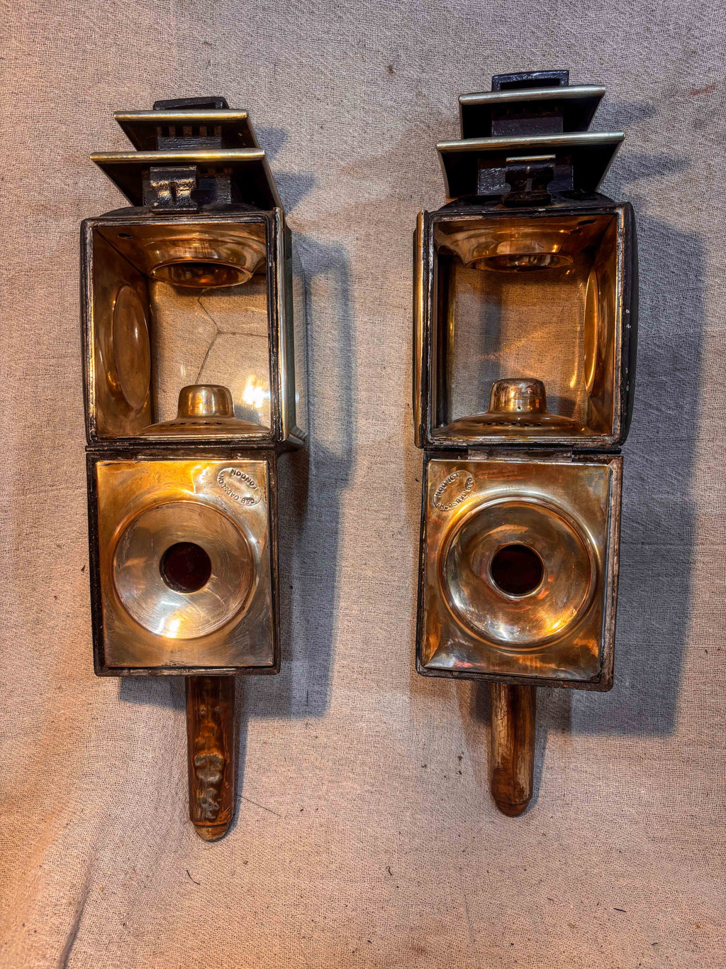 Pair of Antique carriage lamps showing the interior workings on a textured beige background