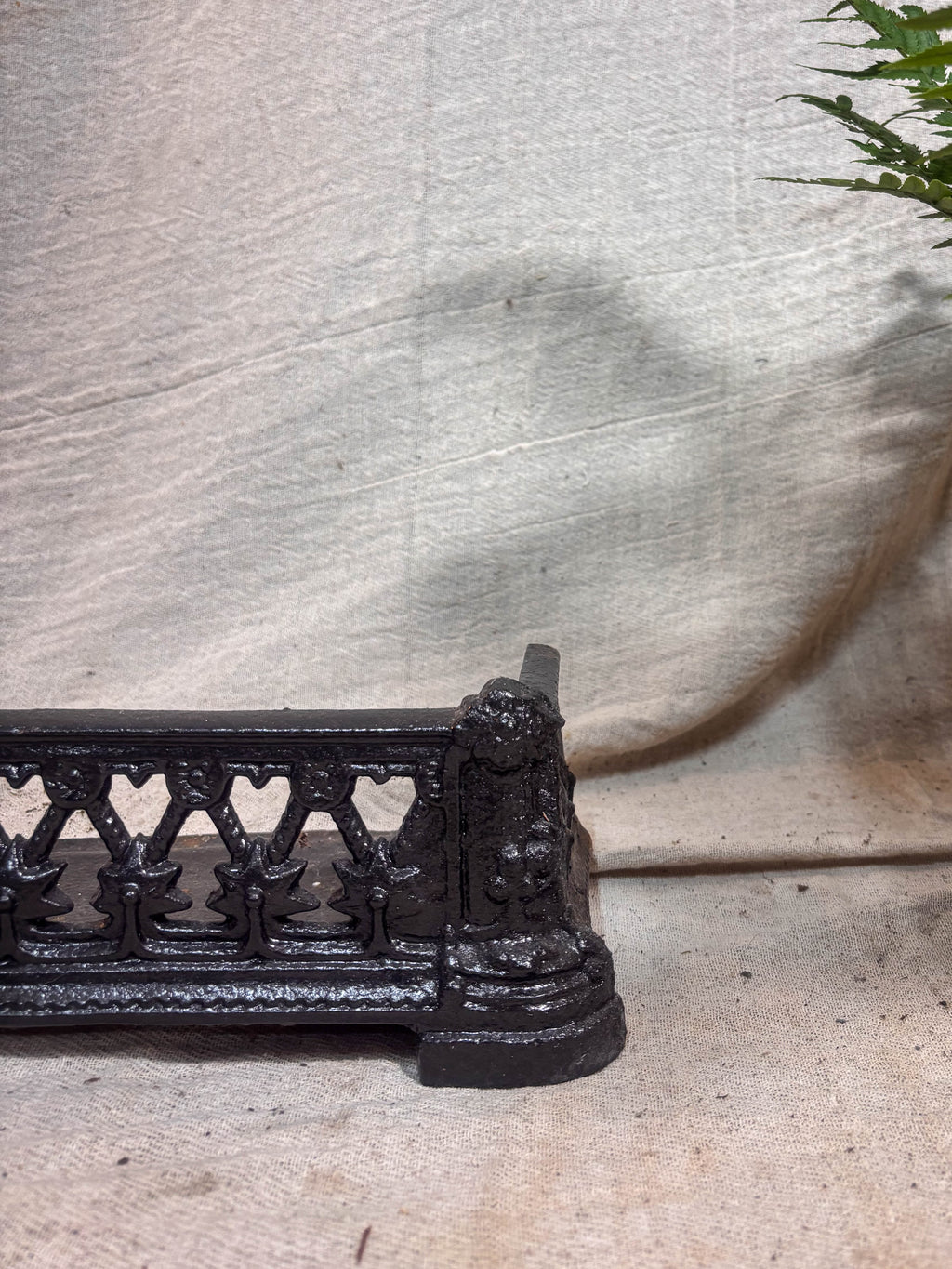 Decorative black metal fireplace fender on a light cloth surface