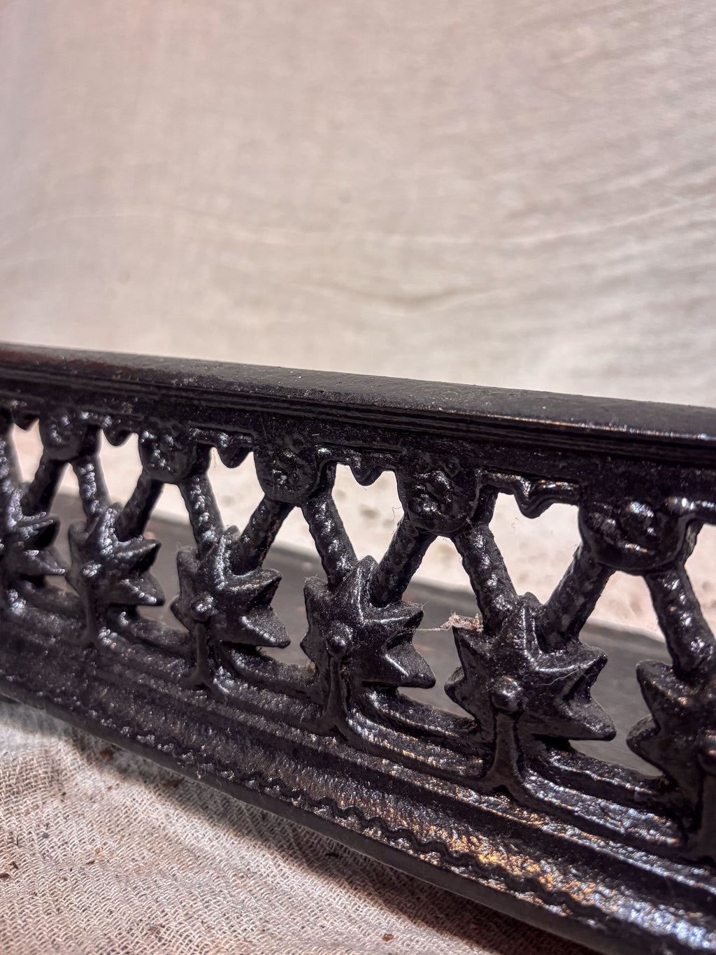 Close-up of a decorative metal fireplace fender with intricate designs on a textured surface.