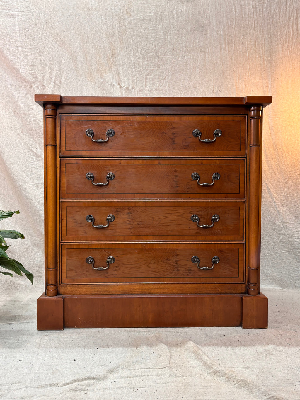 Wooden dresser with four drawers on a textured white background