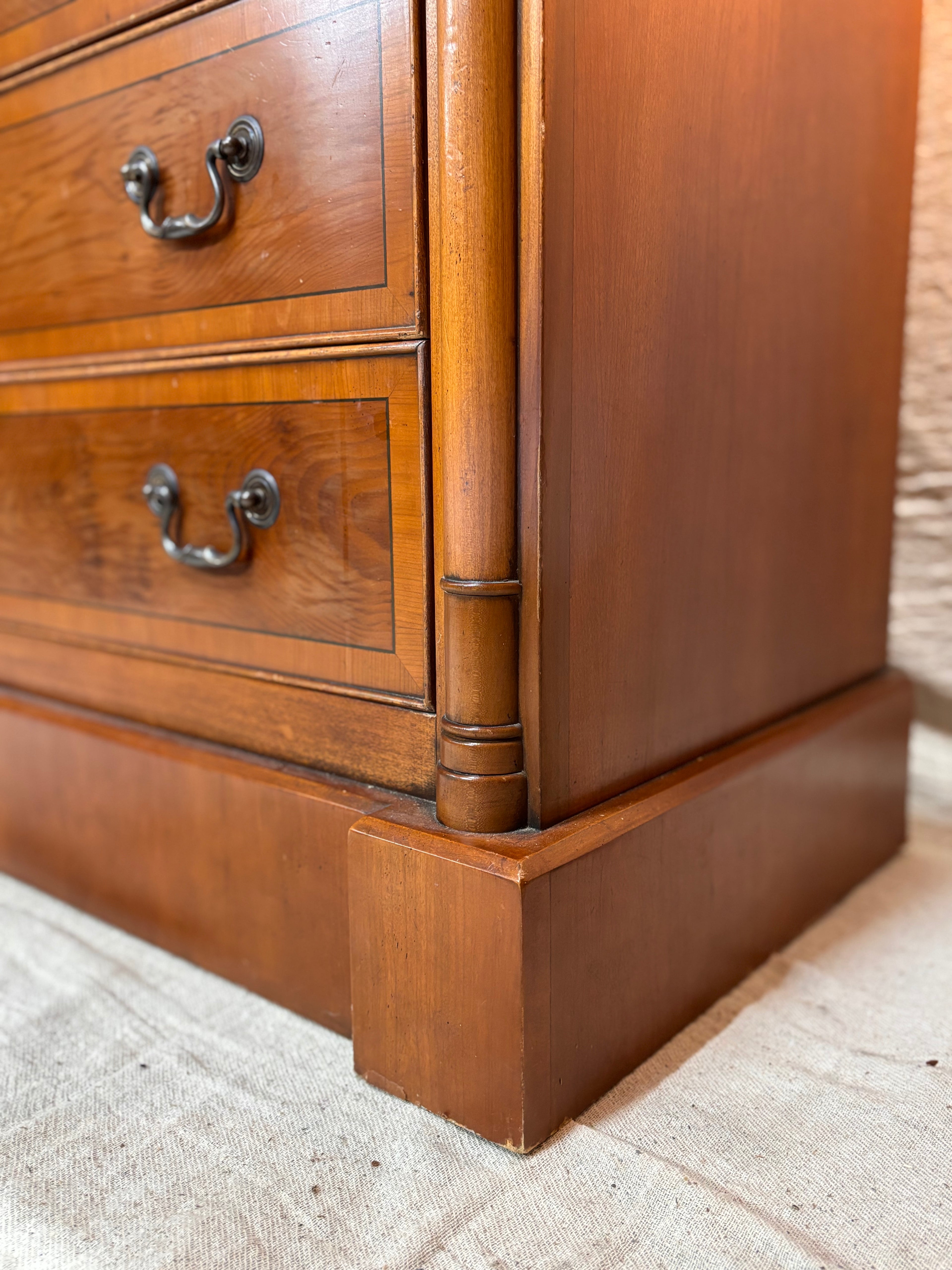 Close-up of a wooden dresser with two drawers on a textured surface.