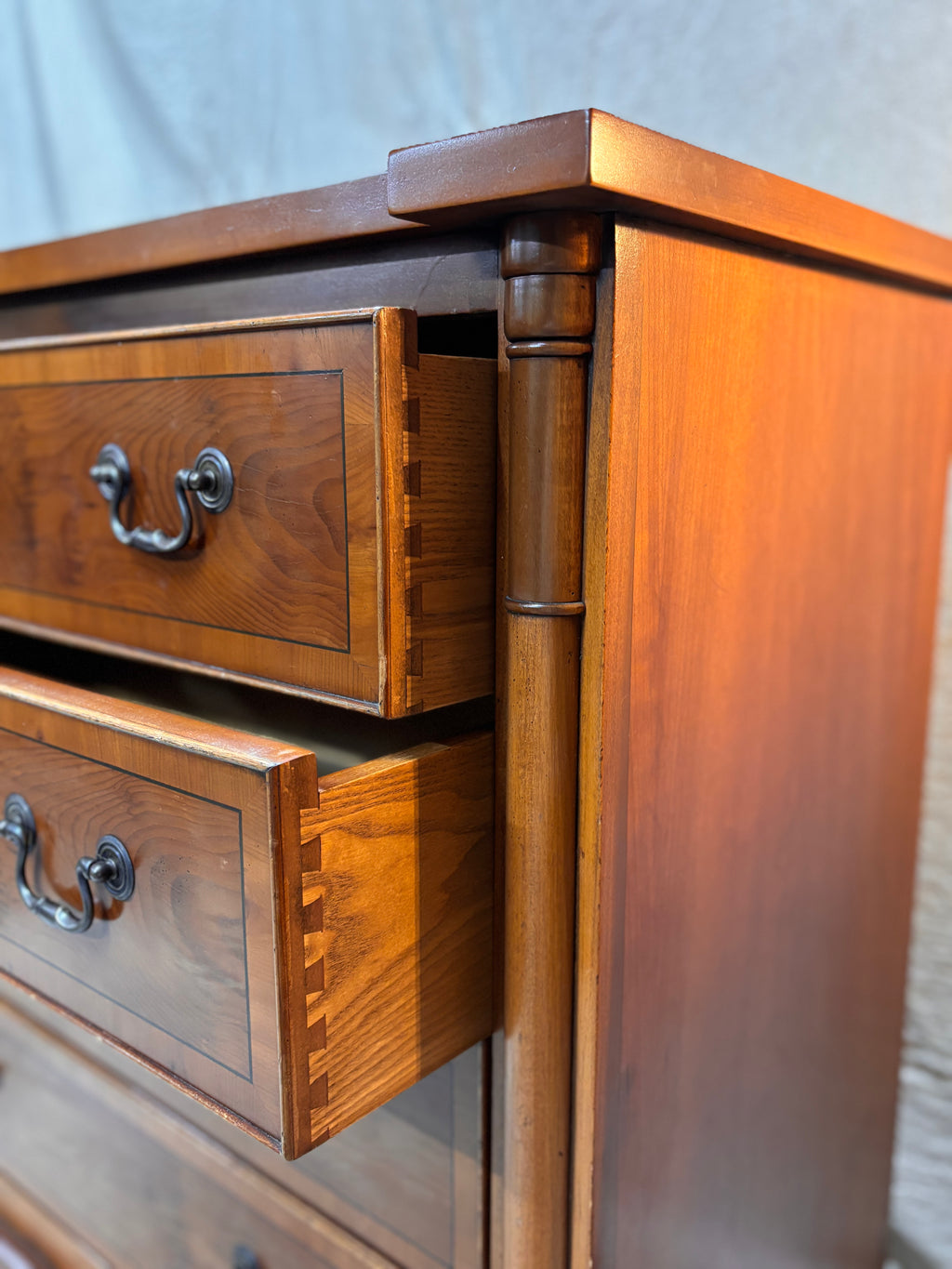 Wooden dresser with open drawers against a neutral background