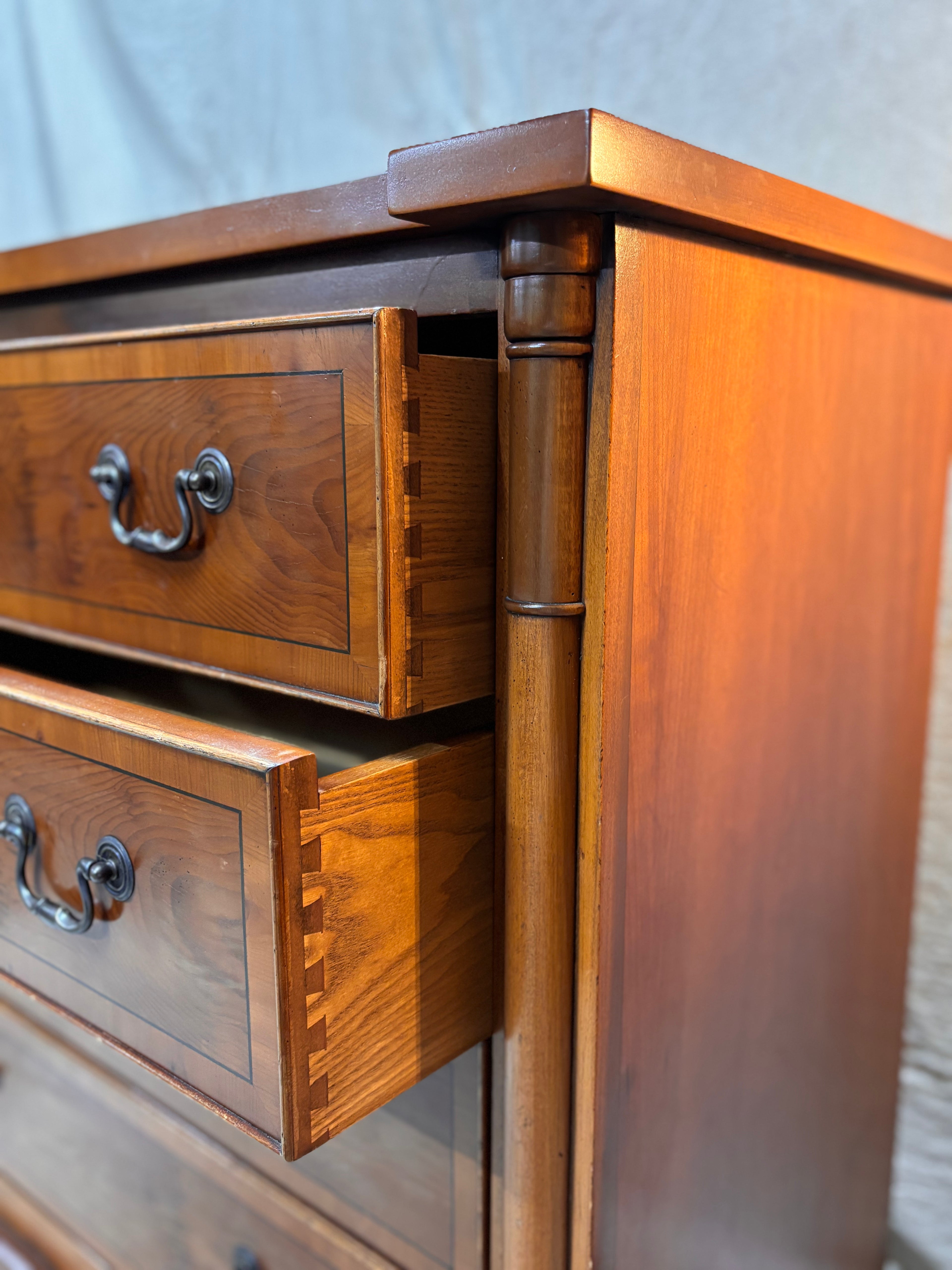 Wooden dresser with open drawers against a neutral background
