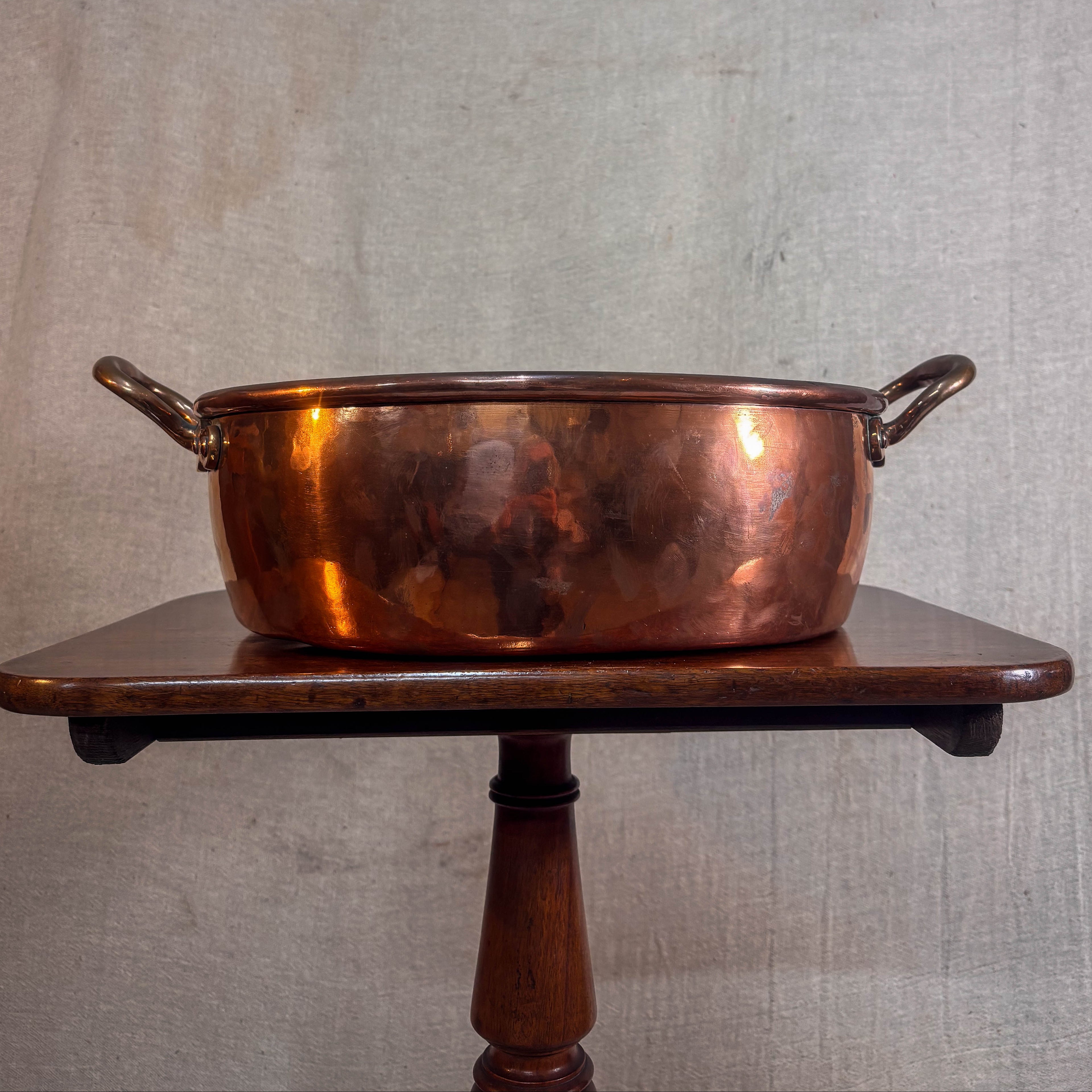 Copper pot on a wooden stand against a textured wall