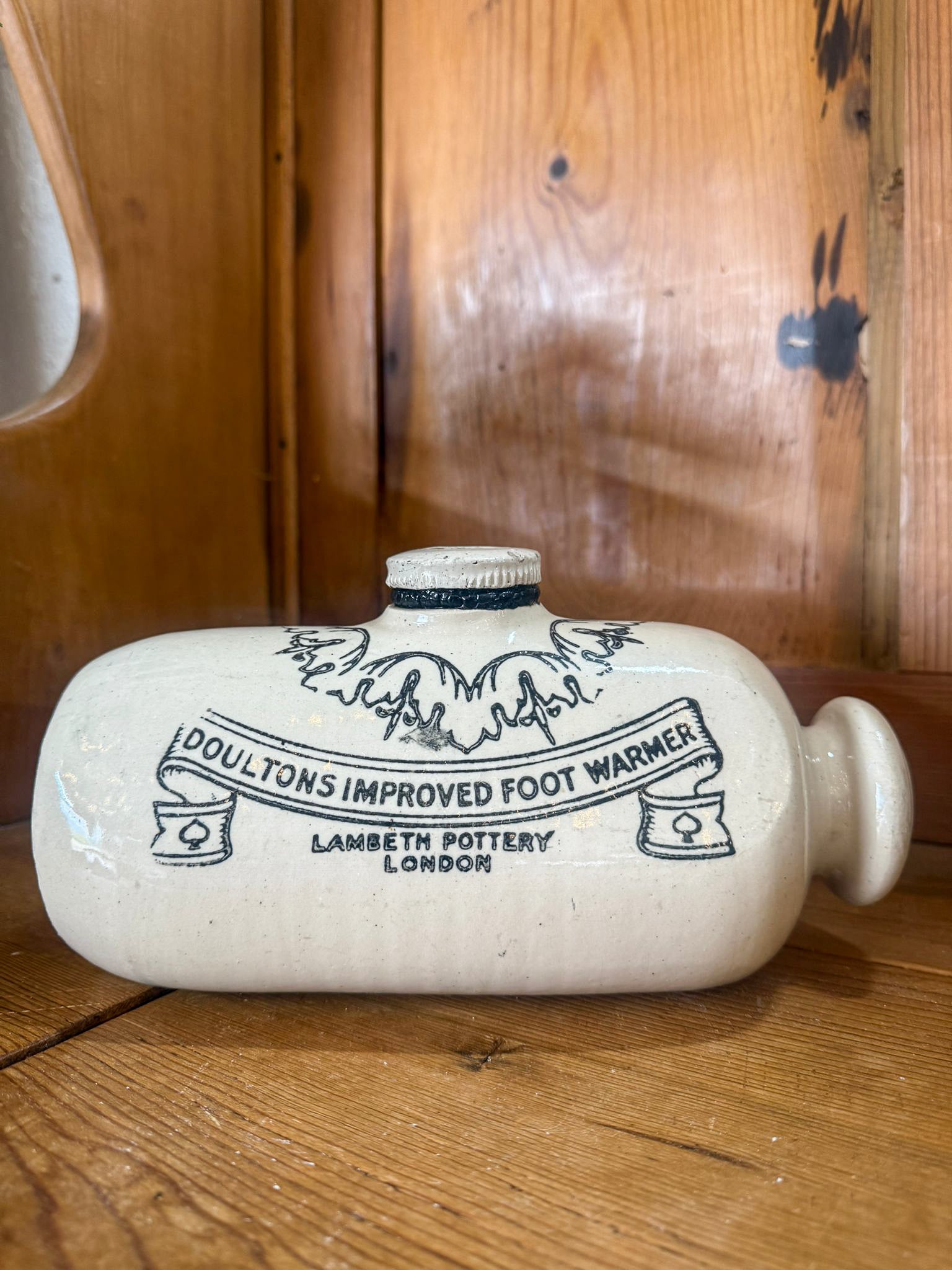 White ceramic foot warmer with black text on a wooden surface