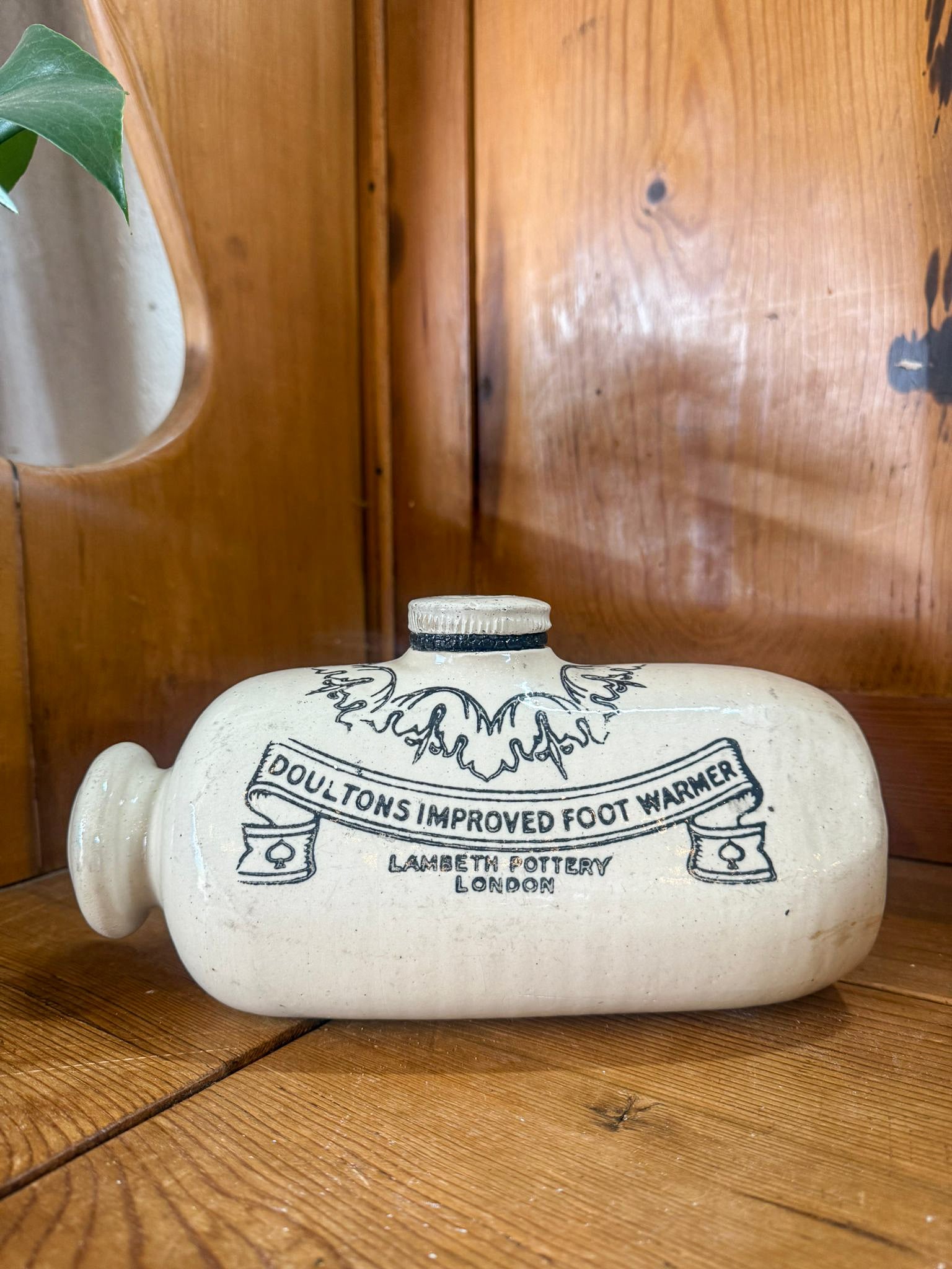 White ceramic foot warmer with black text on a wooden surface