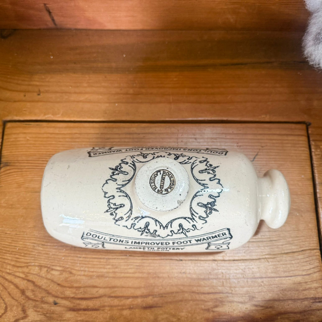 White ceramic foot warmer with black text on a wooden surface