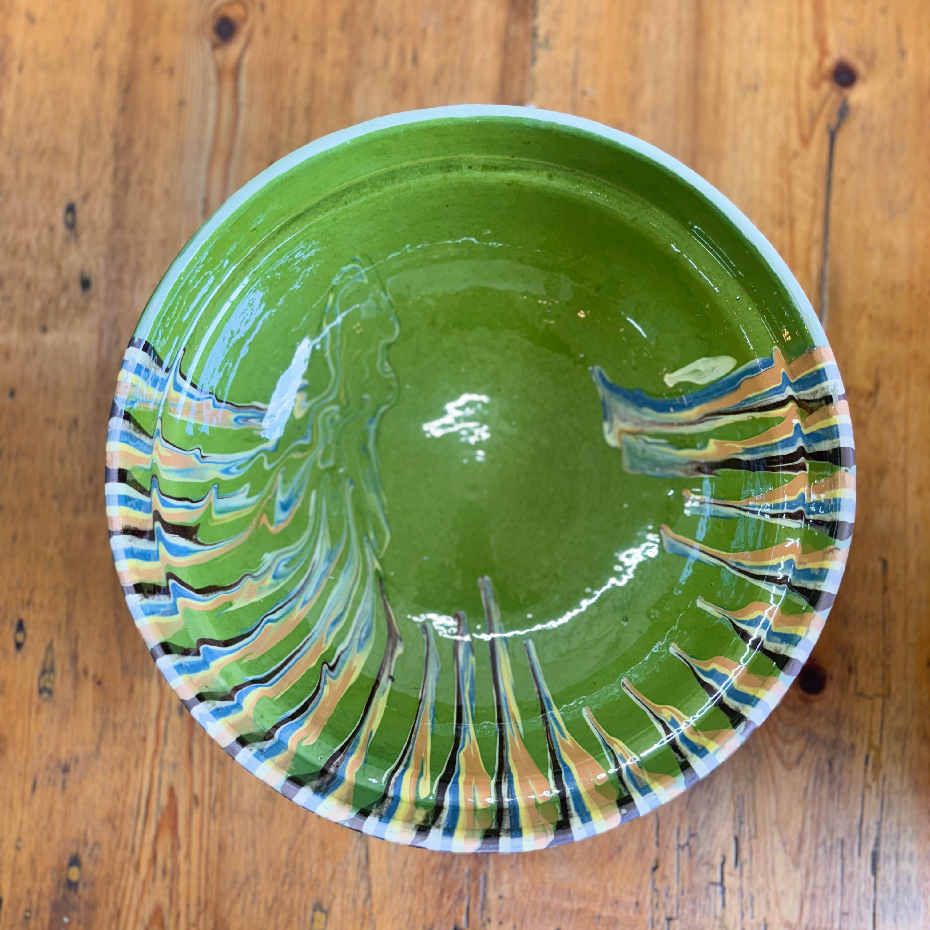 Green ceramic bowl with abstract patterns on a wooden surface