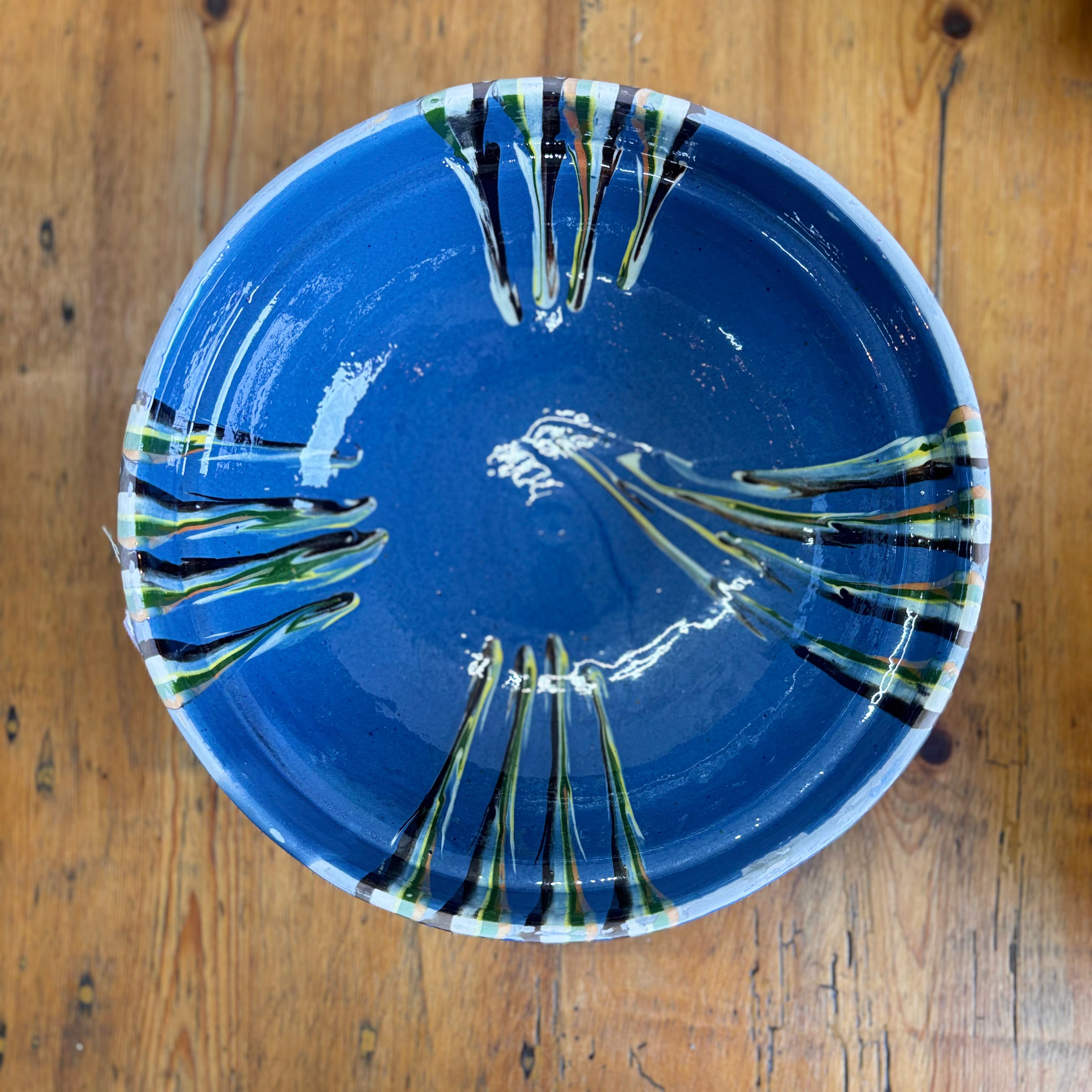 Blue ceramic plate with artistic design on a wooden surface
