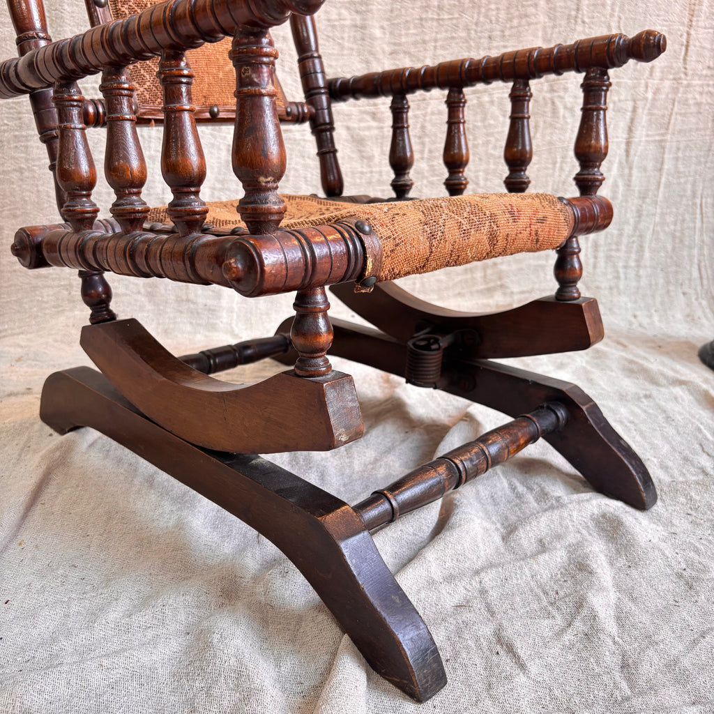 Close-up of an antique wooden rocking chair with a textured surface.