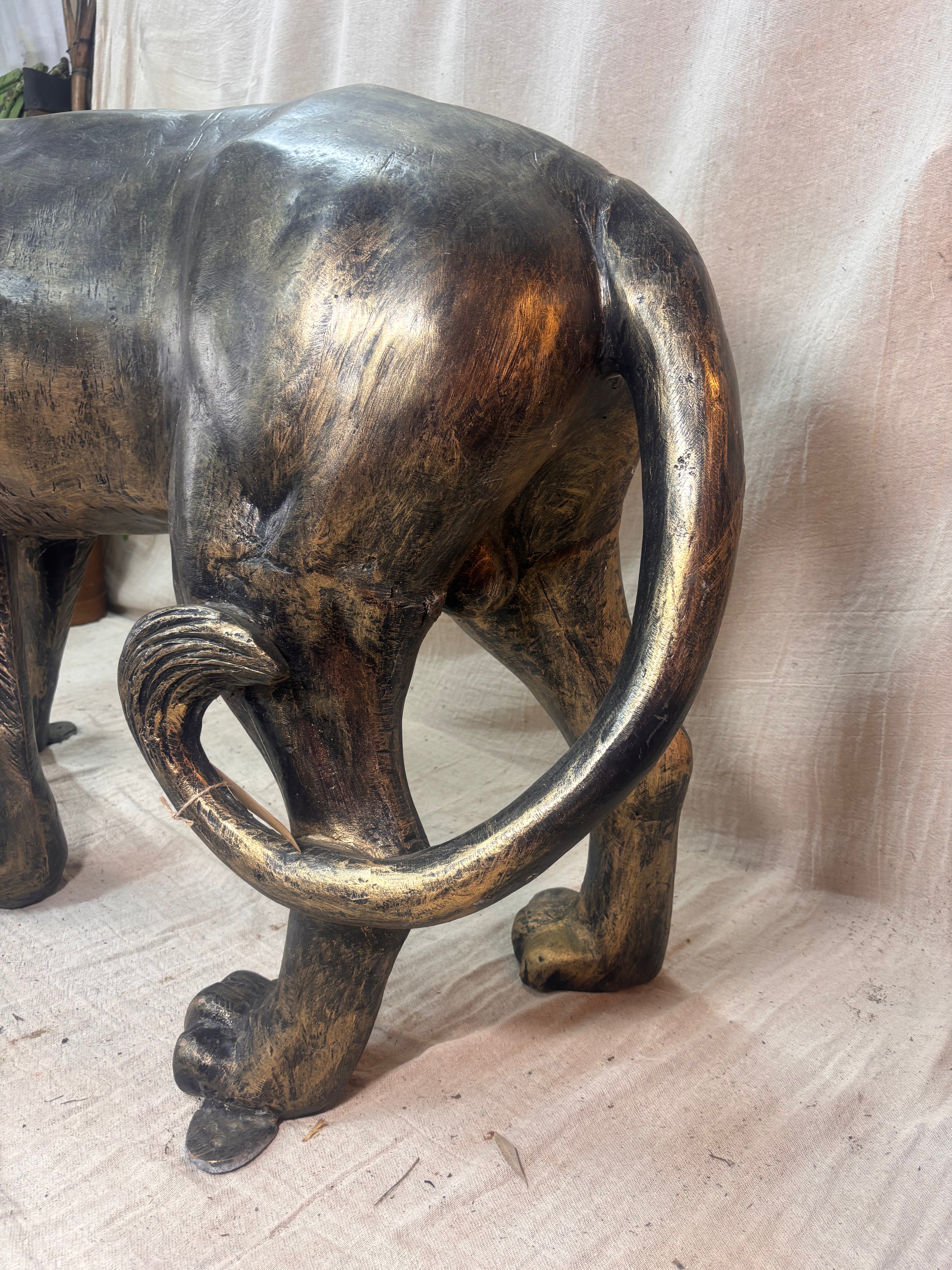 Tail of a Bronze Lion sculpture on a plain surface