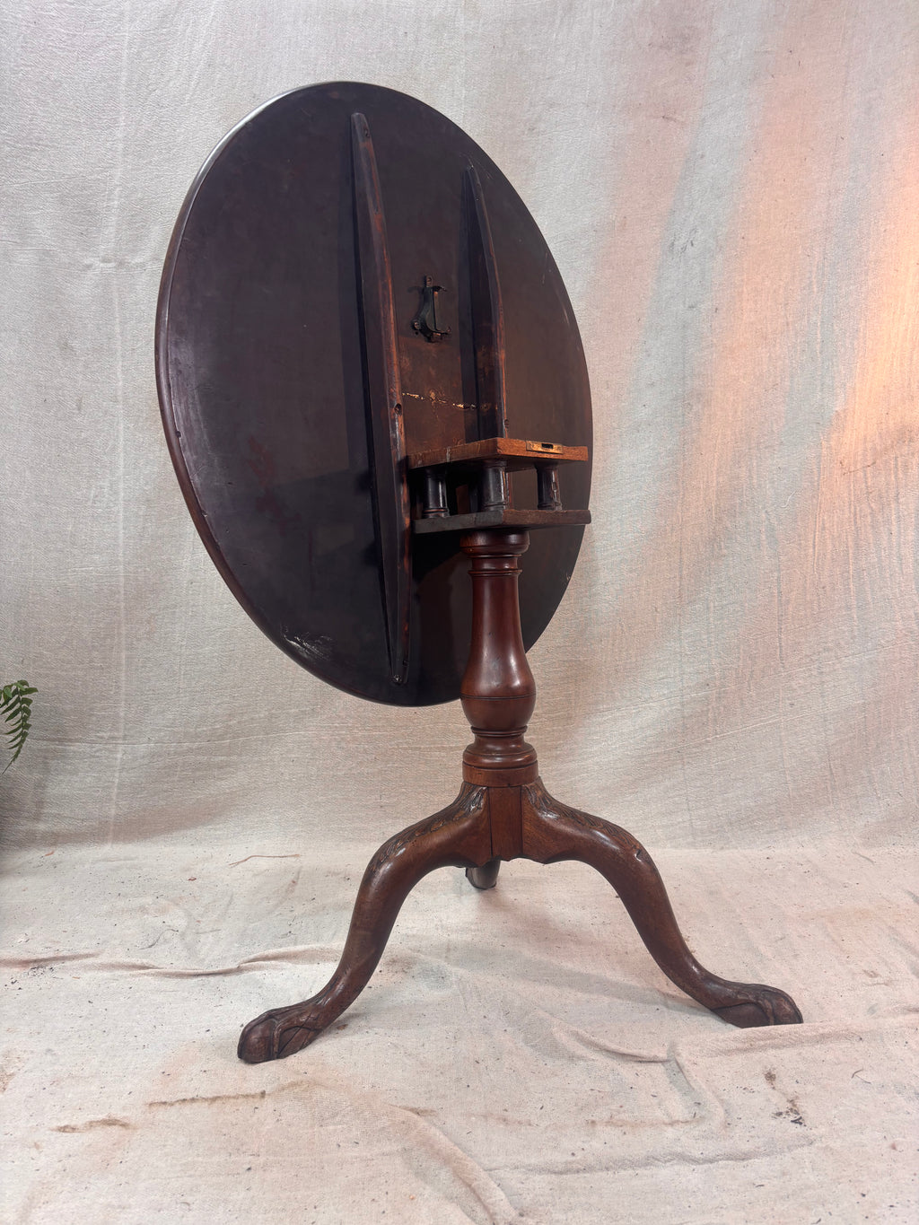 Wooden tripod stand with round top on a textured surface