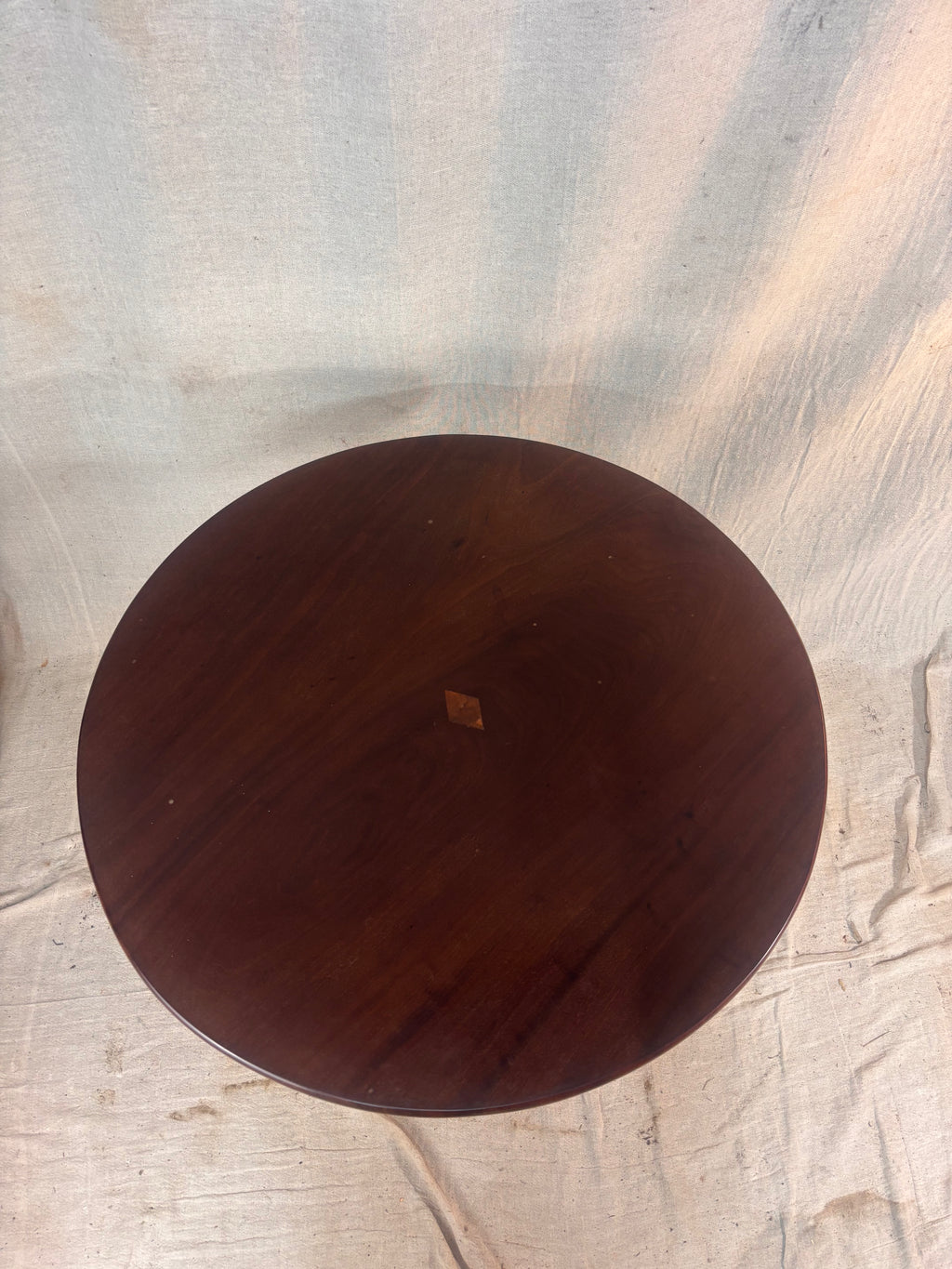 Round wooden table on a textured coloured floor