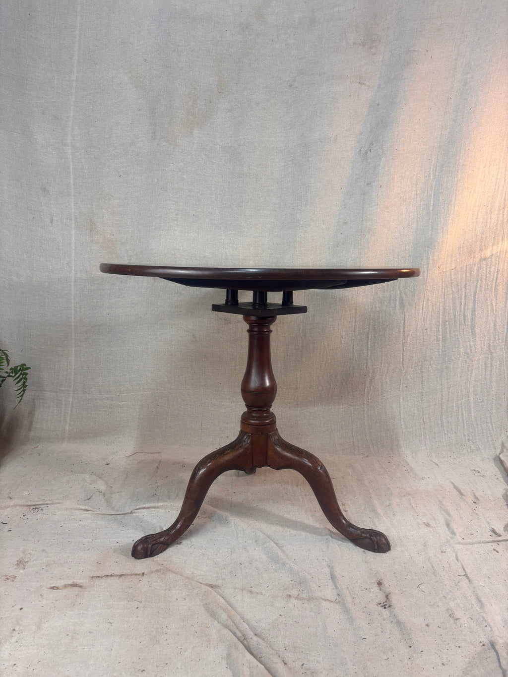 Wooden pedestal table on a textured stone floor with a neutral background