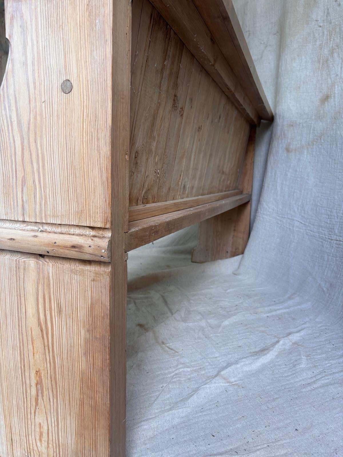 Rear of a wooden pew with a textured white wall background