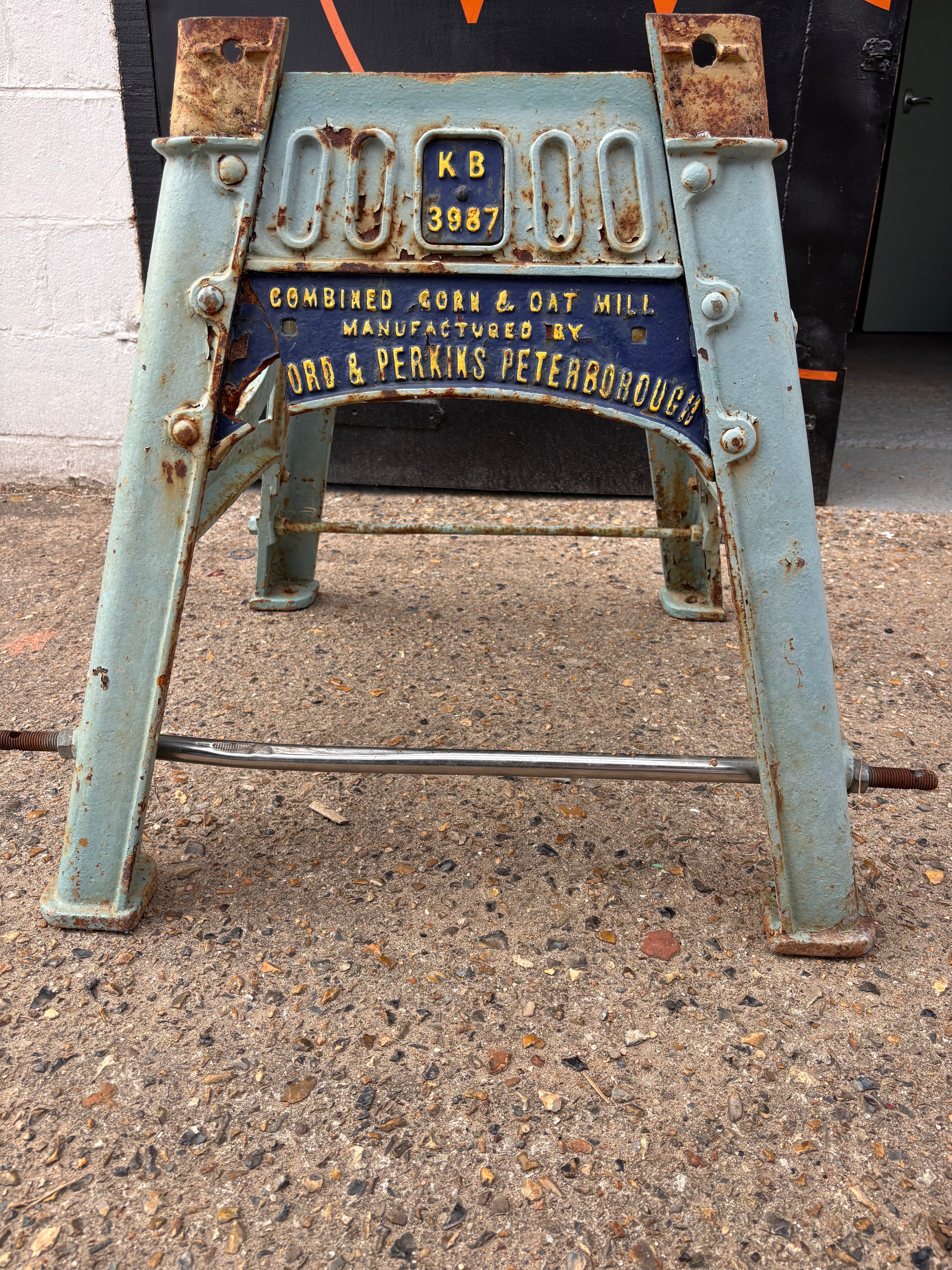 Rustic metal structure with 'KB' and '3987' markings on a concrete surface.