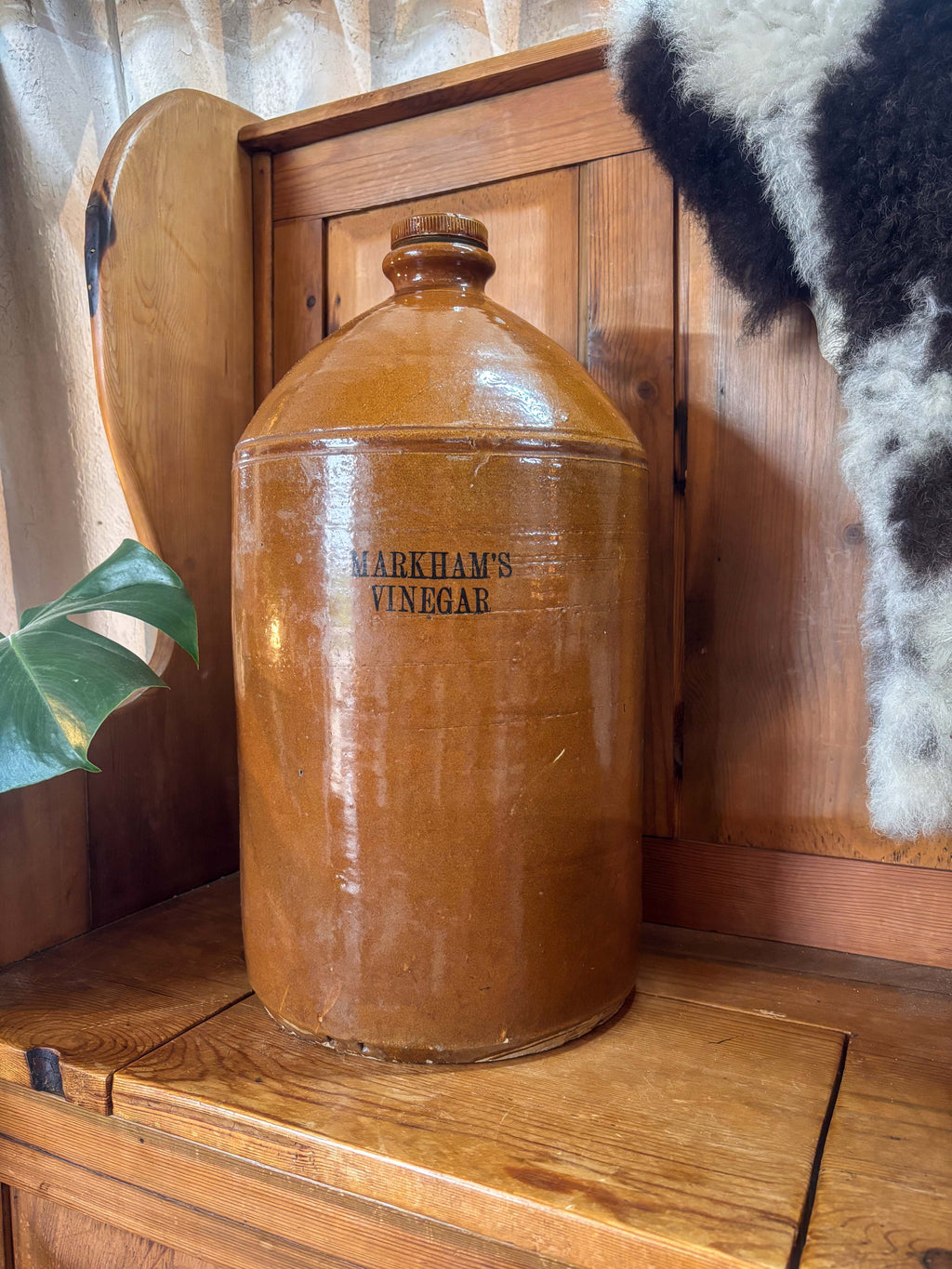 Vintage jar of Markham's Vinegar on a wooden surface with a wooden cabinet in the background.