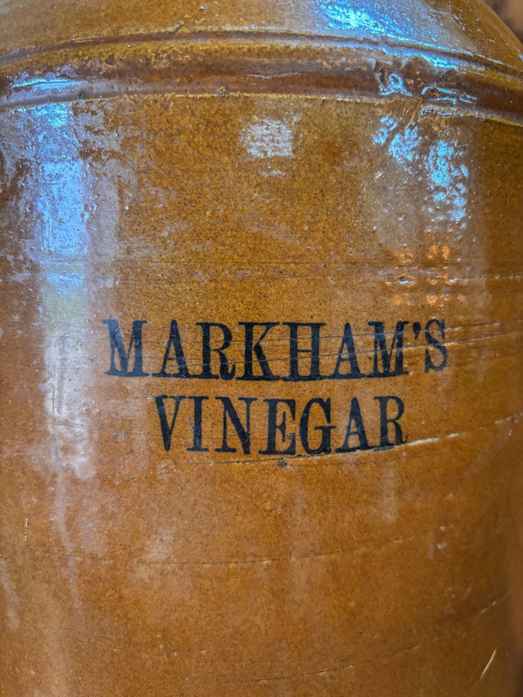 Brown jar with 'Markham's Vinegar' branding on a reflective surface