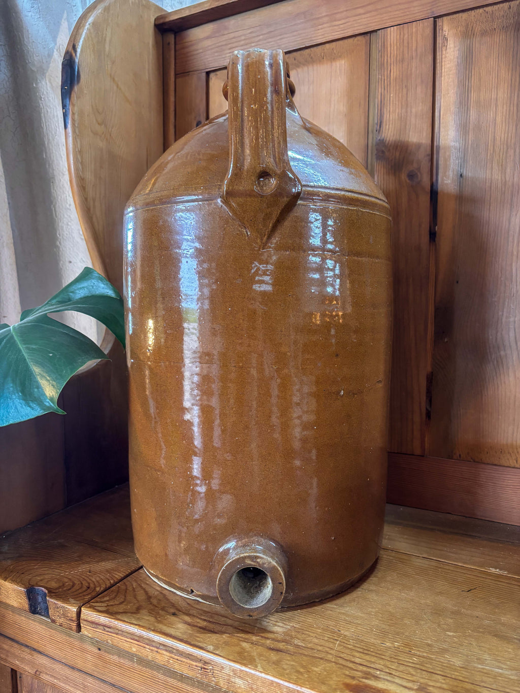 Brown ceramic jar with a handle on a wooden surface