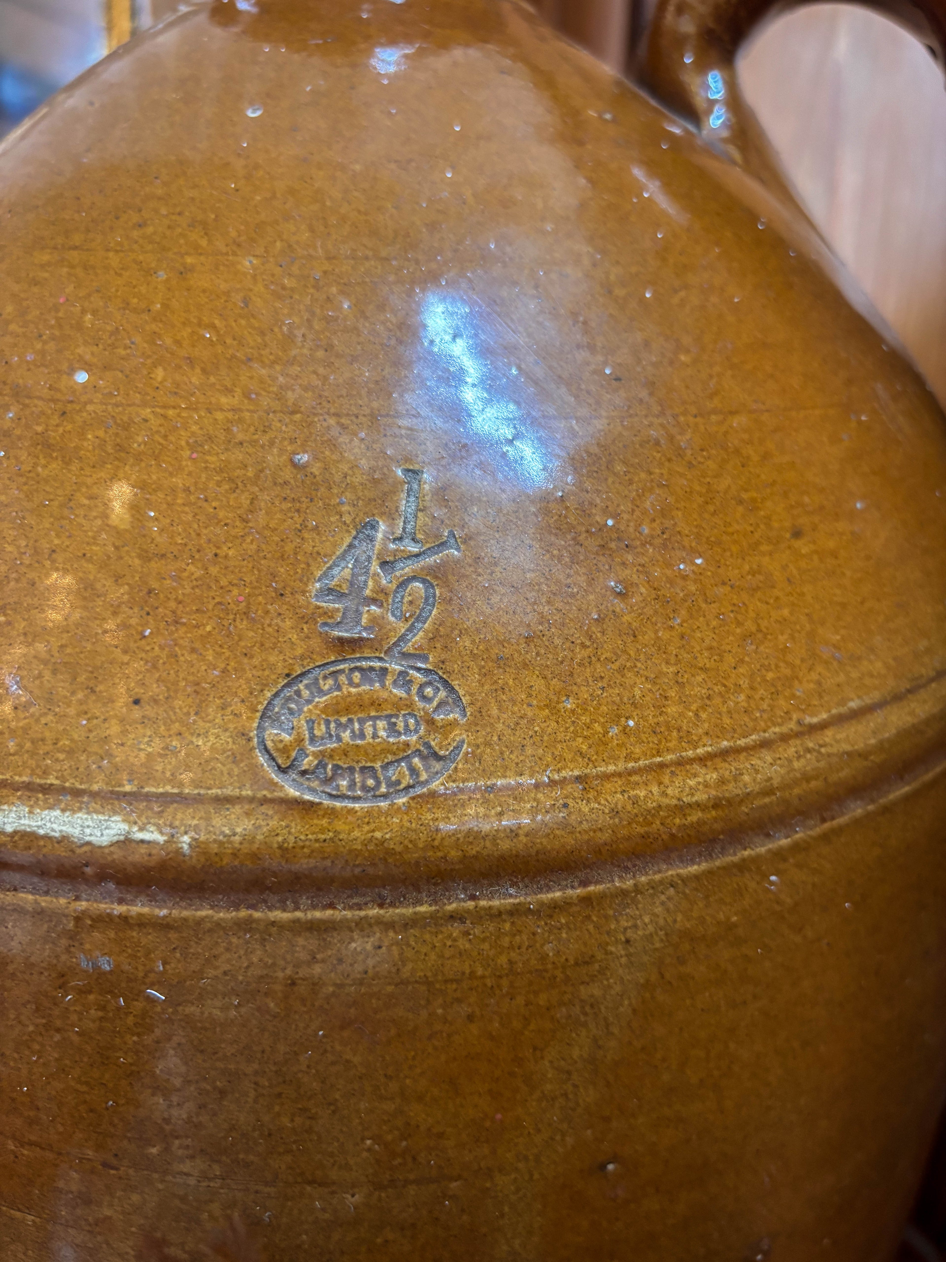 Brown ceramic jar with a visible brand logo on a blurred background