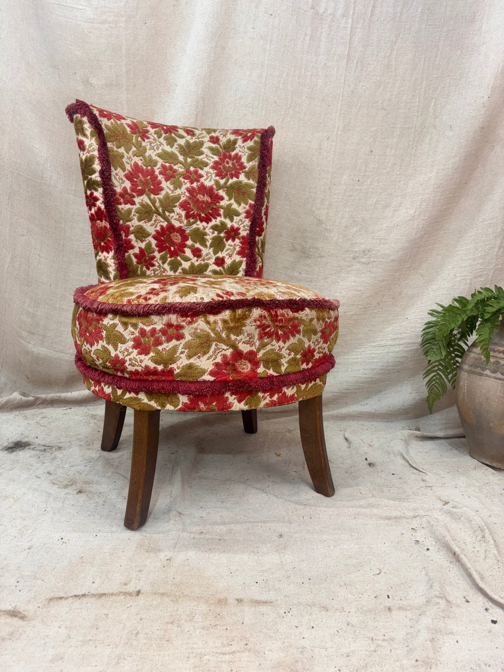 Small floral-patterned chair with wooden legs against a plain background