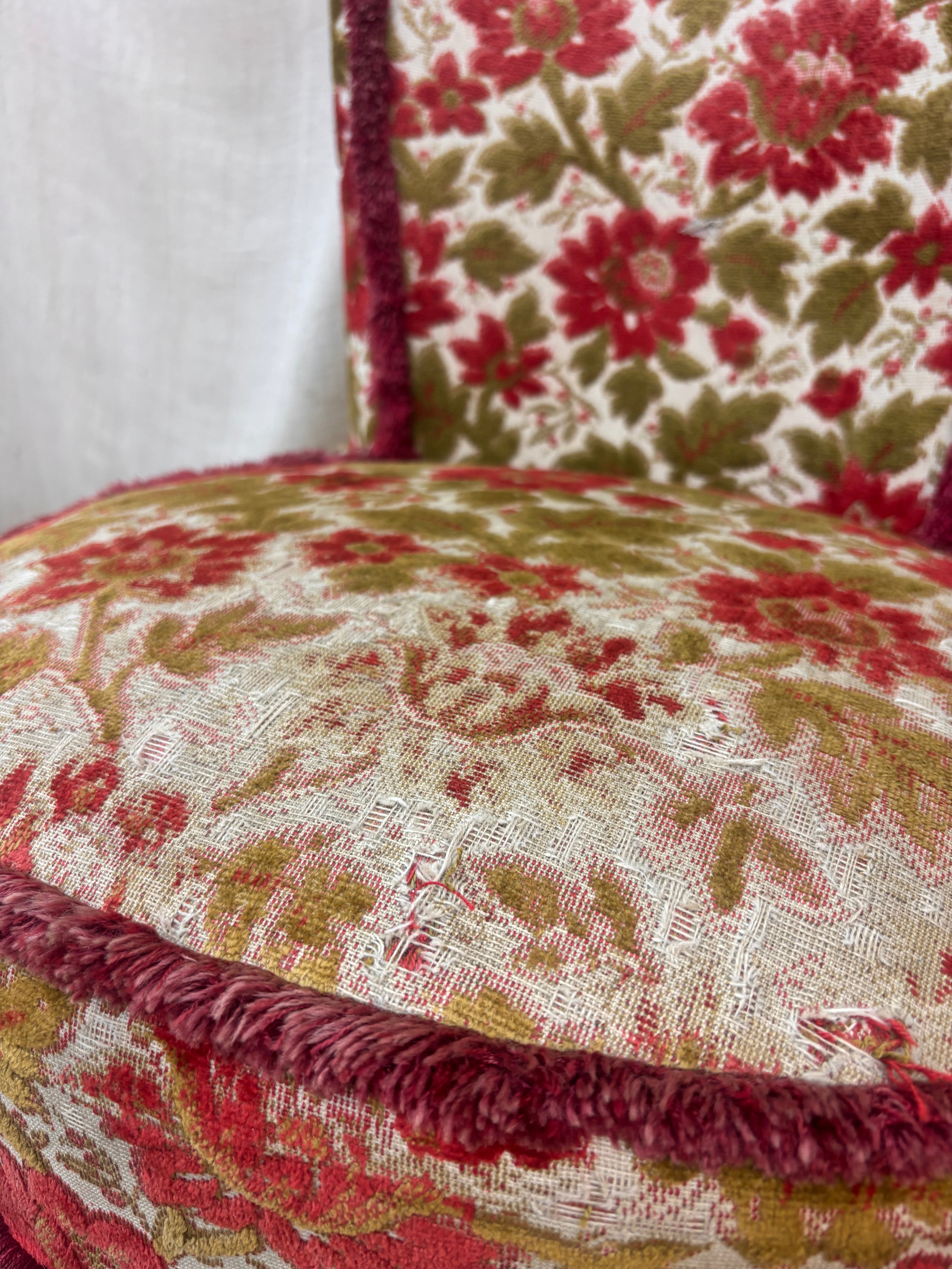 Close-up of a floral-patterned fabric with red, green, and beige colors.