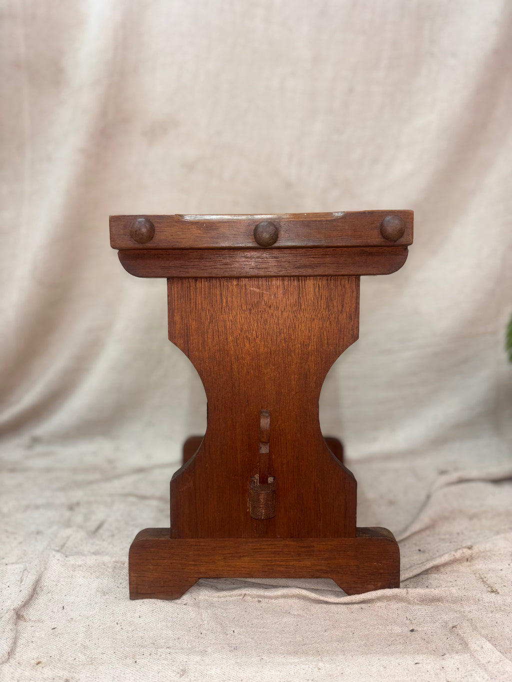 Wooden stool with decorative elements on a beige fabric background