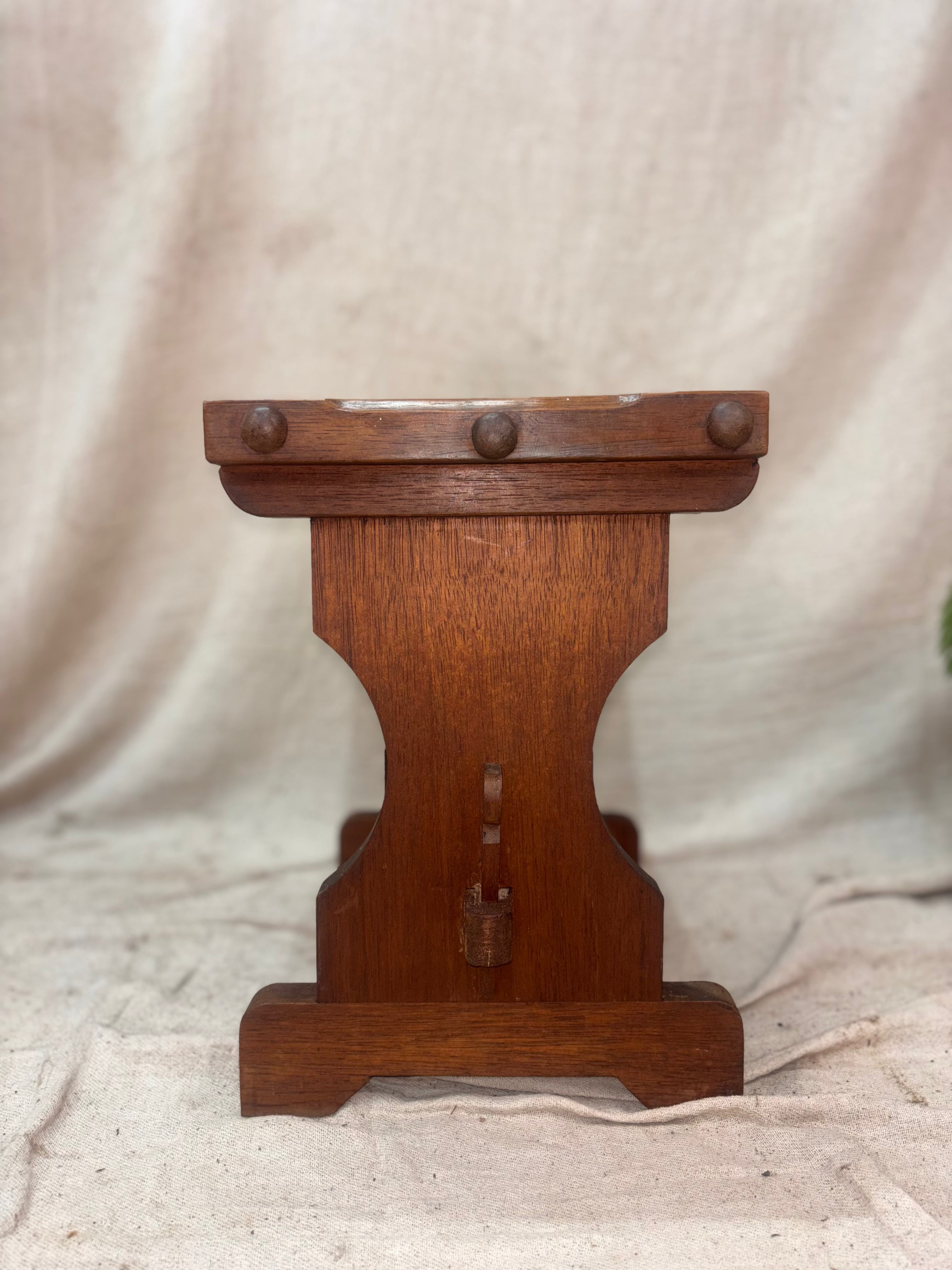 Wooden stool with decorative elements on a beige fabric background