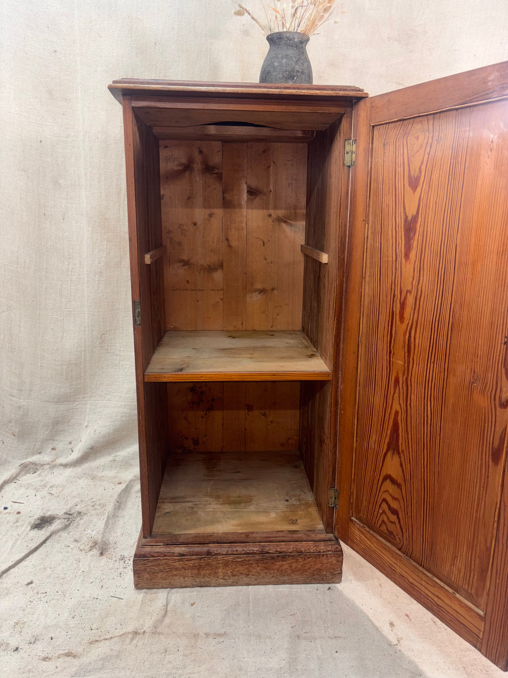 Wooden cabinet with open door on a textured surface