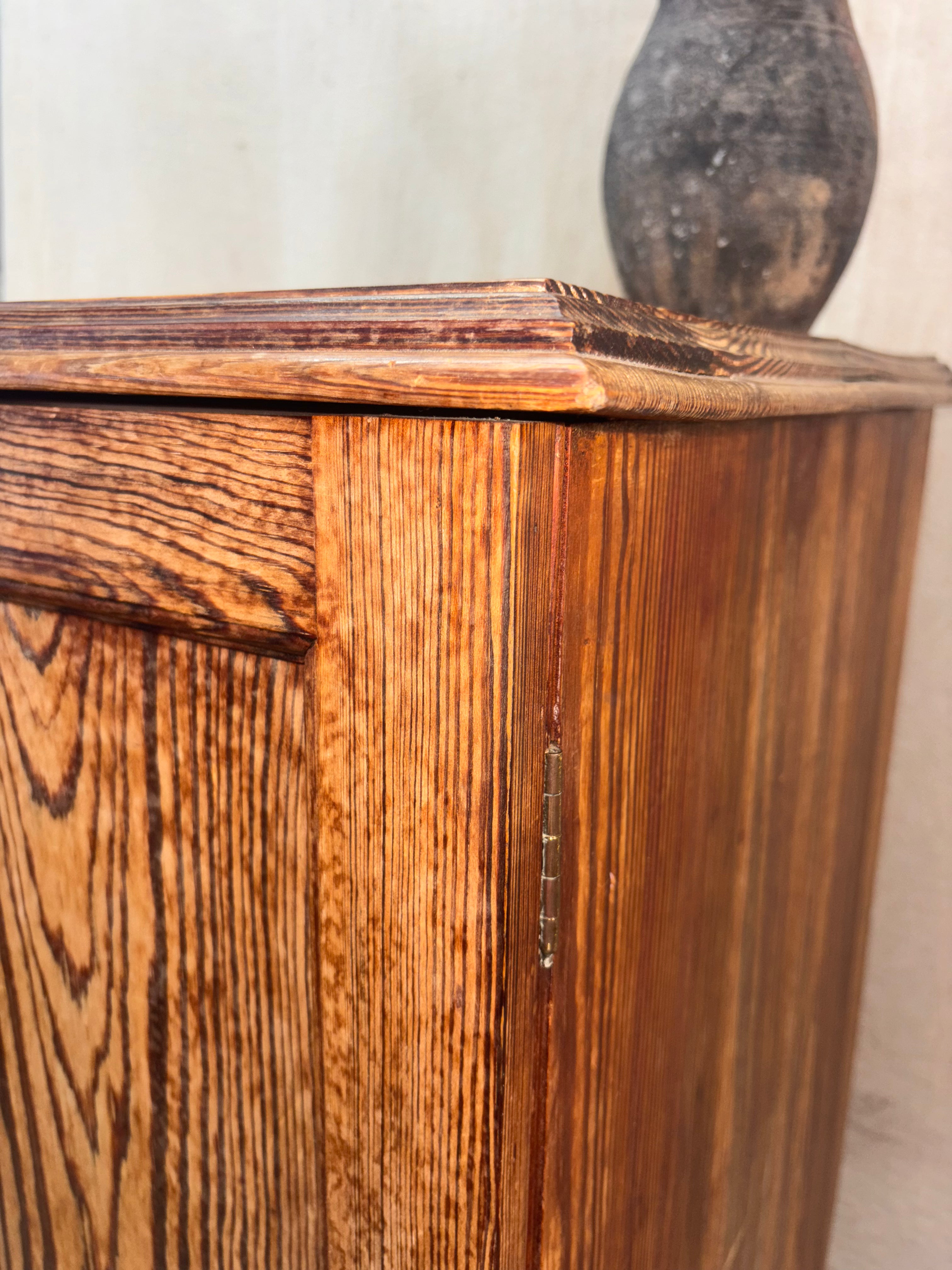 Wooden cabinet with a textured surface and a vase in the background