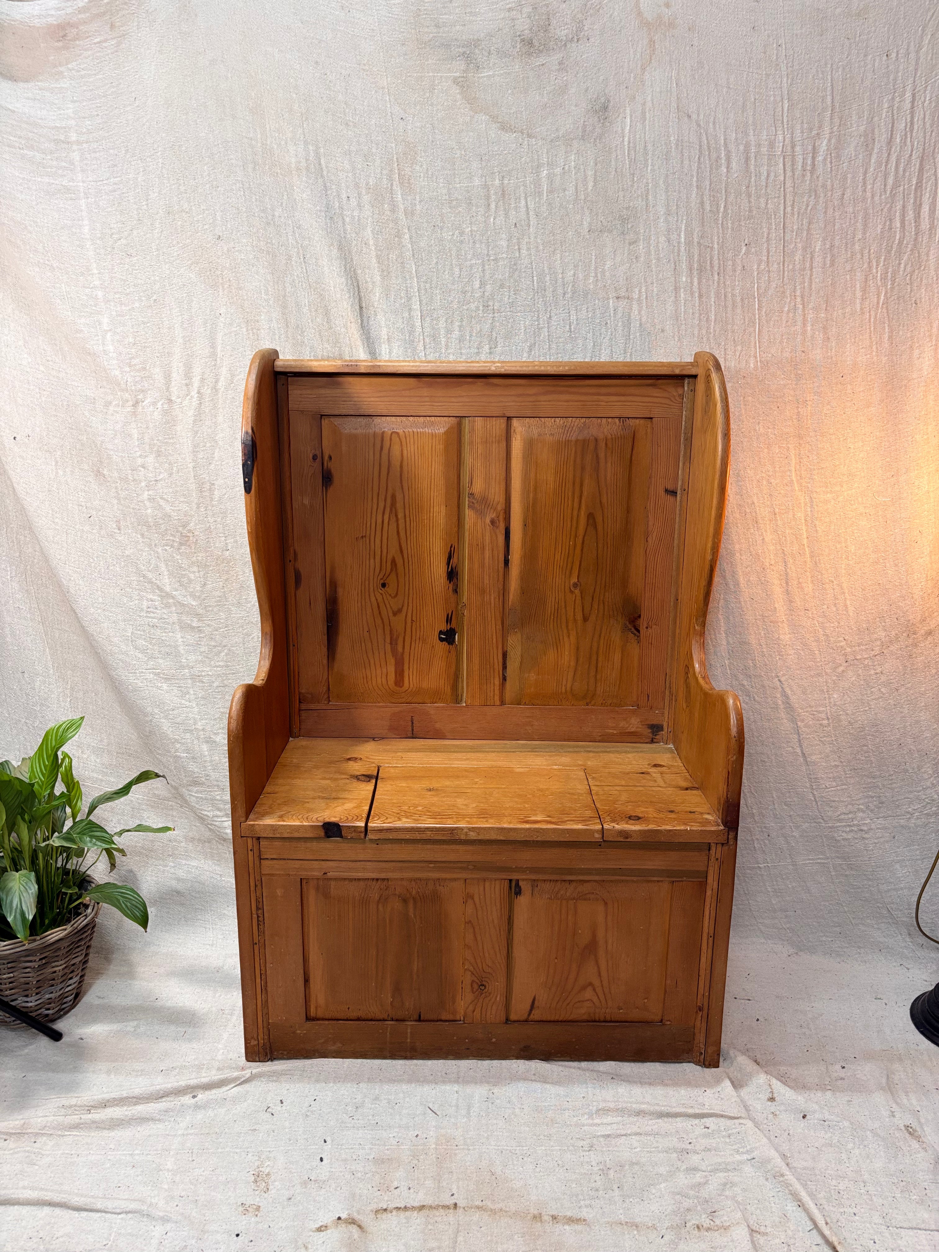 Wooden bench with storage compartments against a textured white wall.