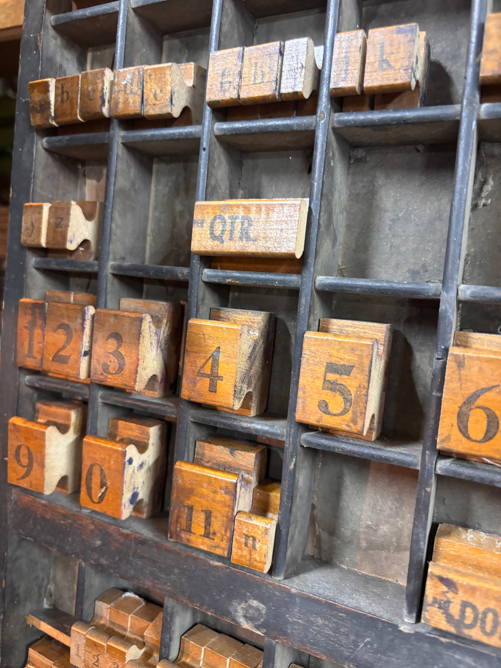 Collection of wooden printing blocks with numbers and letters on a metal tray.