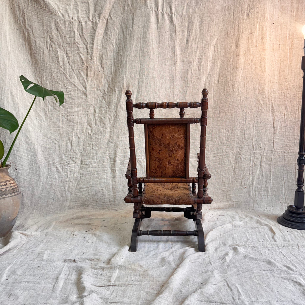 Vintage wooden rocking chair against a textured white backdrop