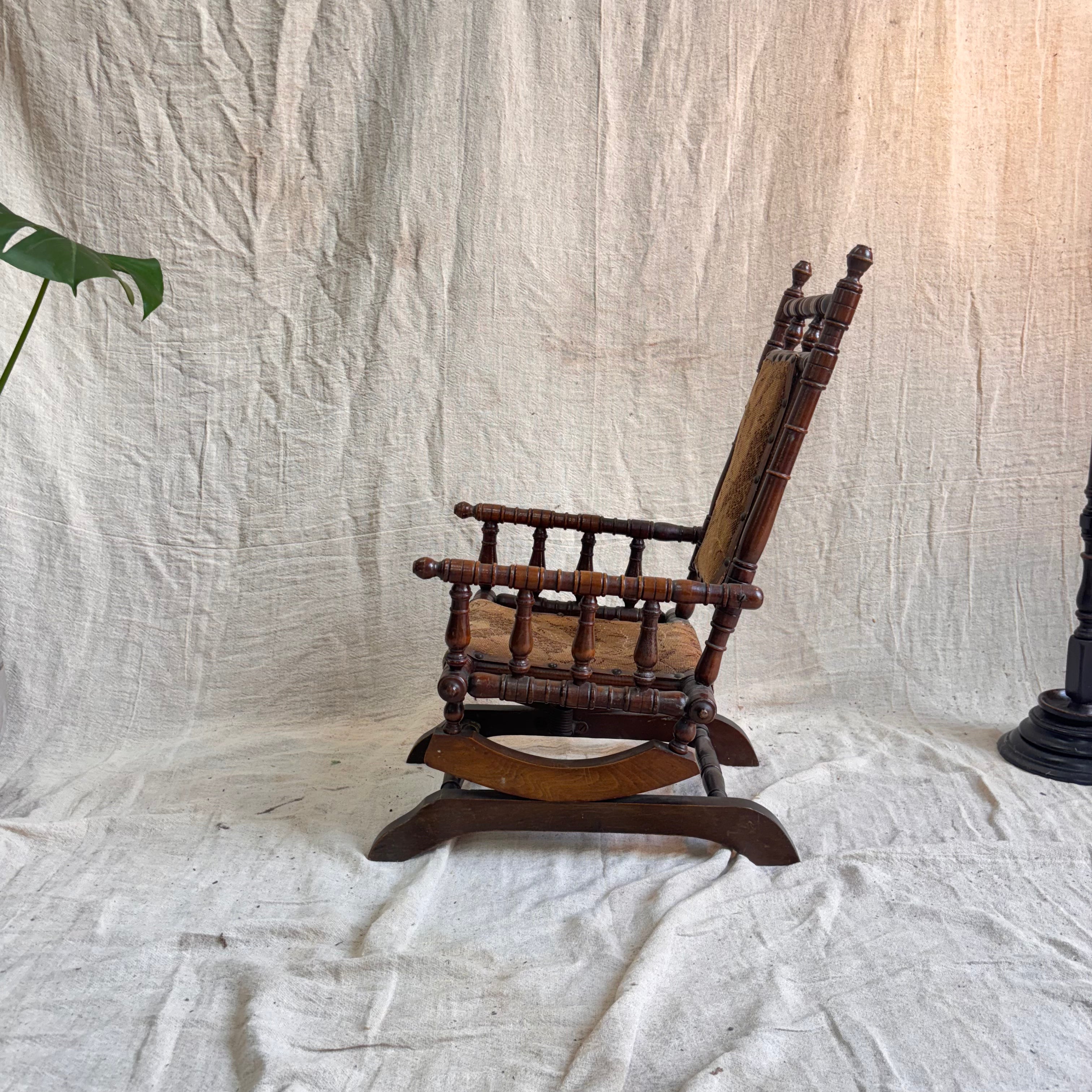 Small wooden rocking chair on a textured white fabric background