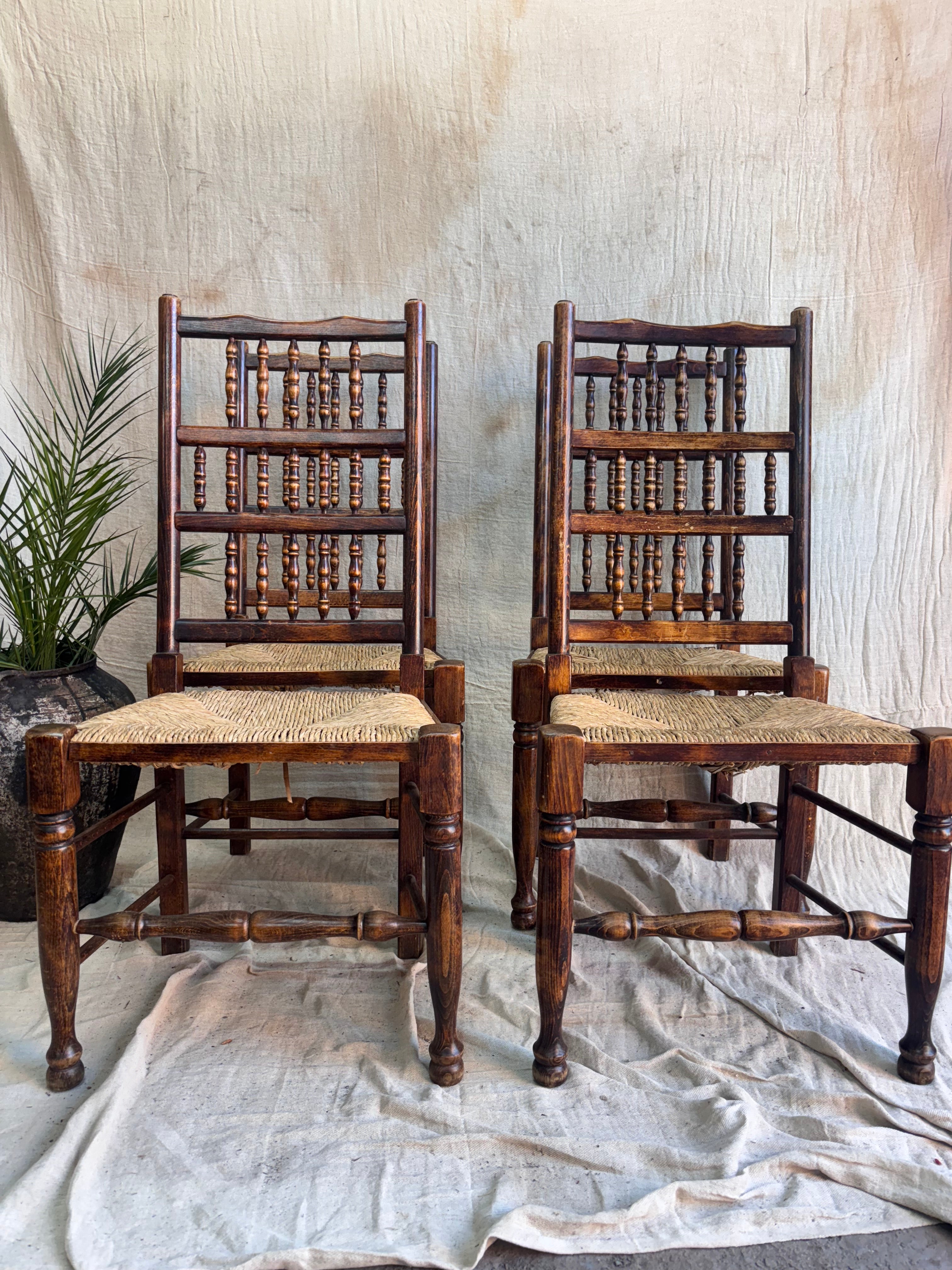 Four wooden chairs with woven backrests on a textured surface.