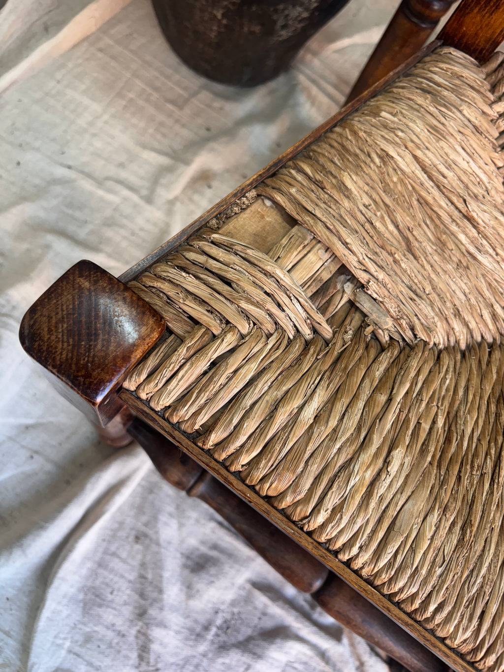 Close-up of a woven chair seat with wooden frame on a textured surface