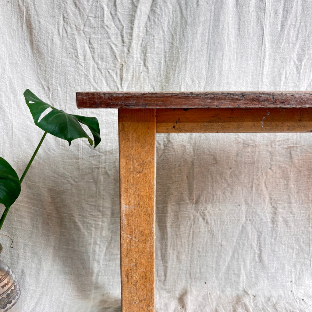Wooden table with a plant against a textured white wall