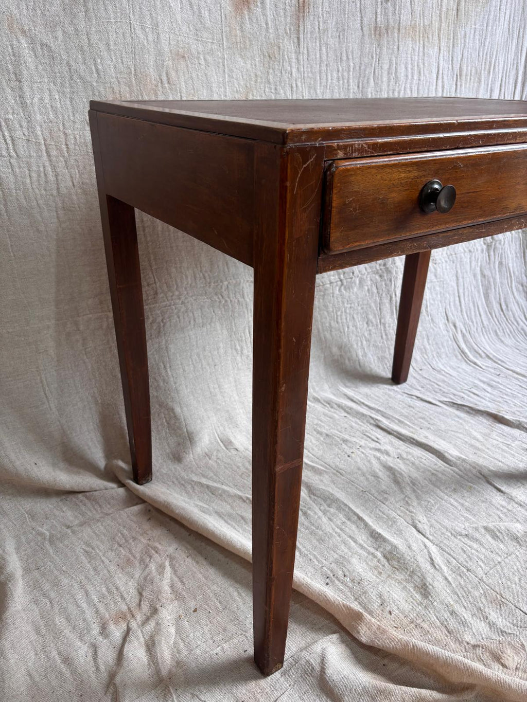 Wooden desk with a single drawer on a textured white background