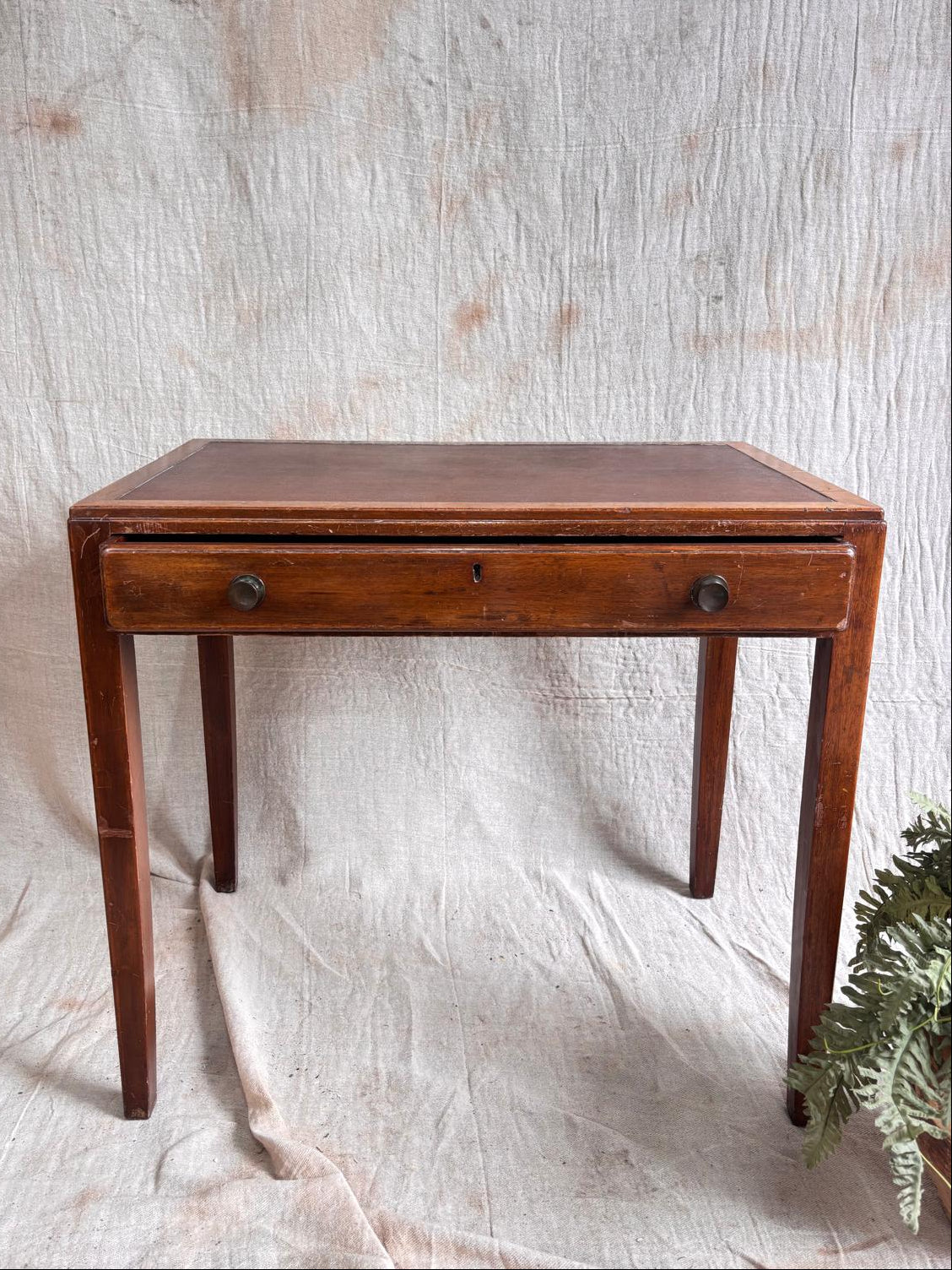 small Wooden desk with a single drawer on a textured white background