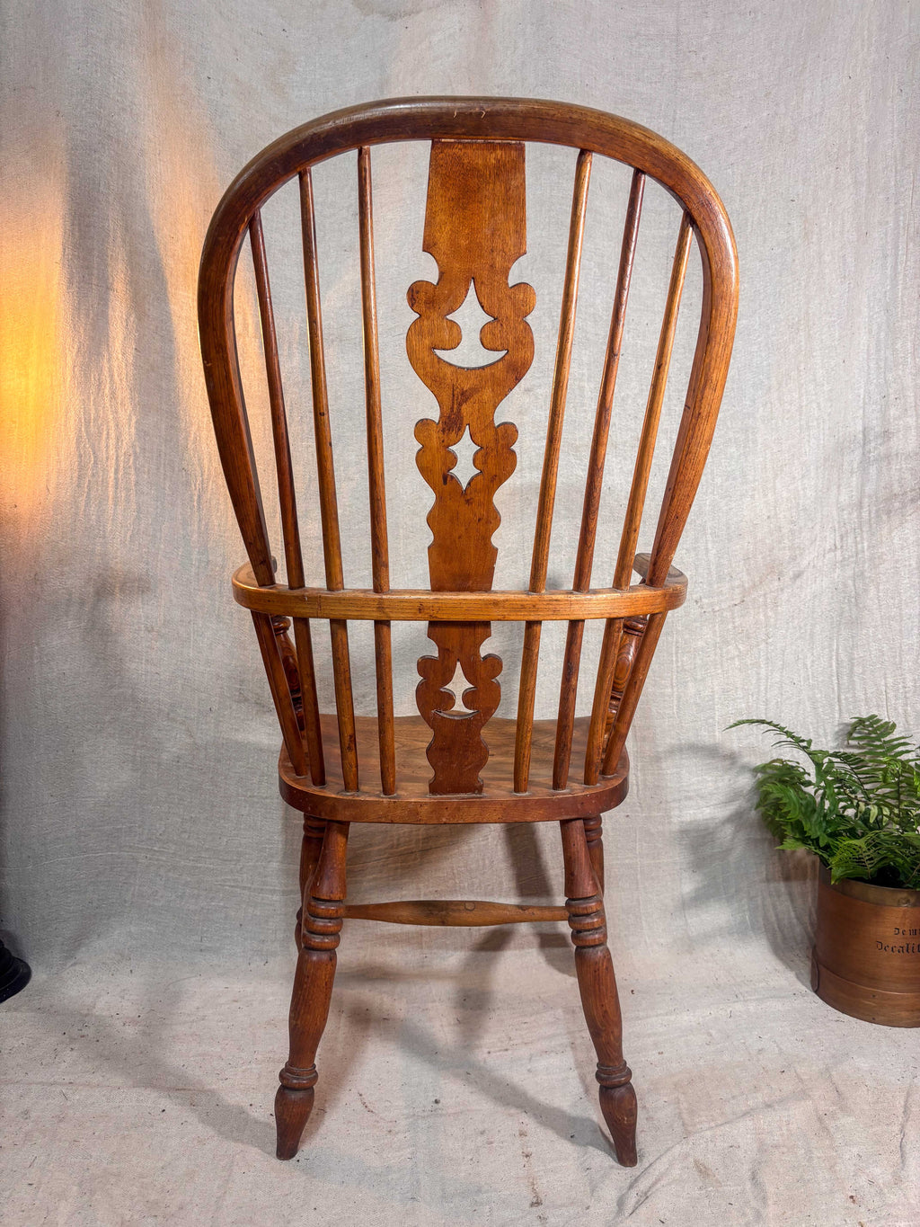 Wooden chair with intricate back design on a textured wall background