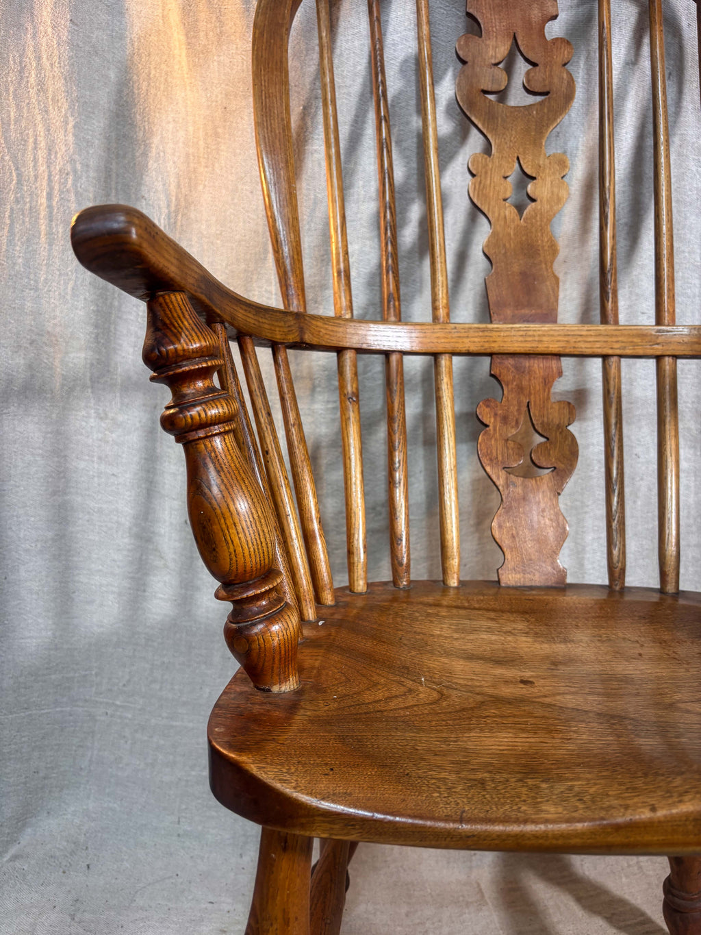Wooden chair with intricate backrest design on a textured fabric background