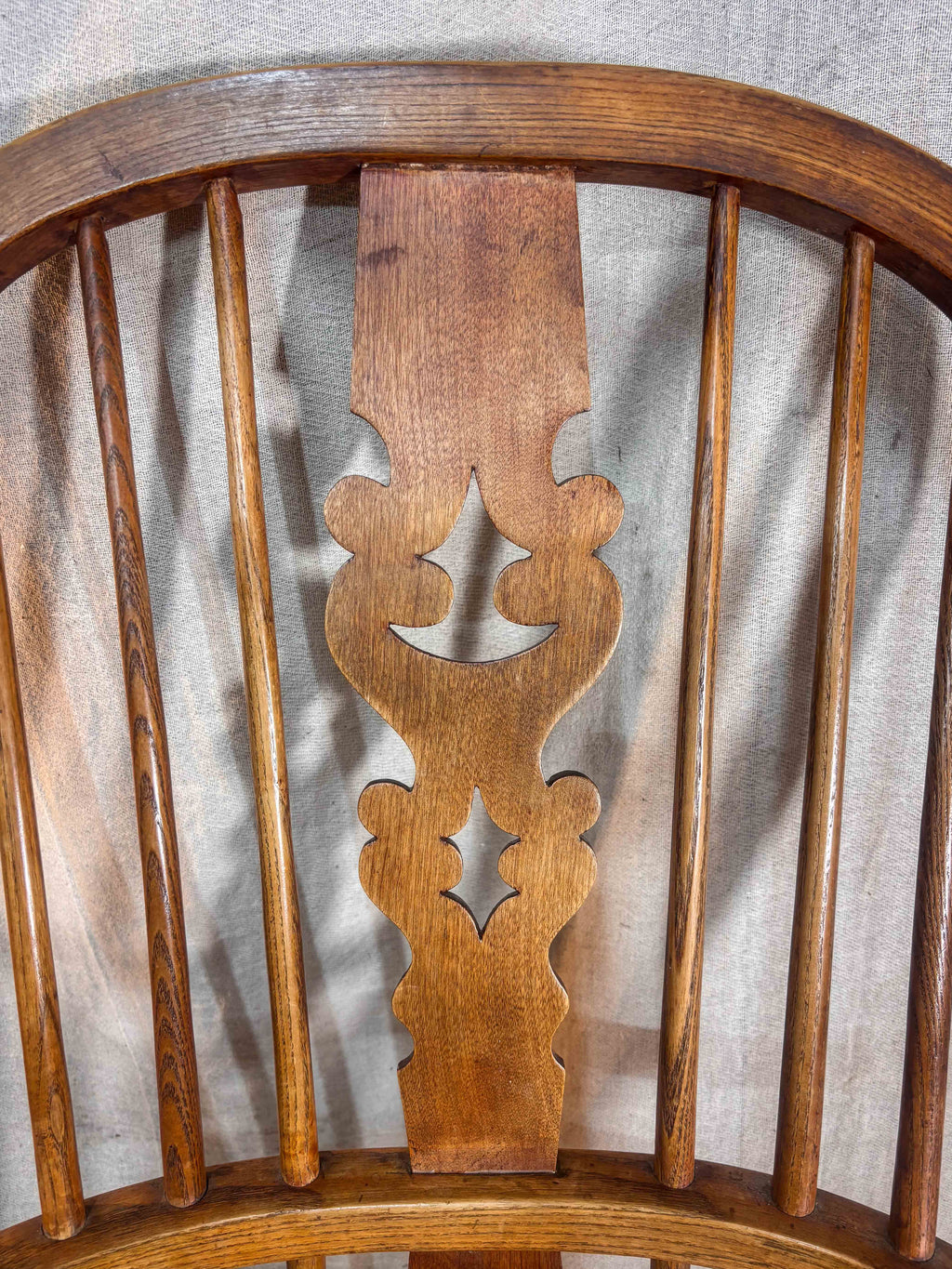 Close-up of a wooden chair back with intricate carvings on a neutral background
