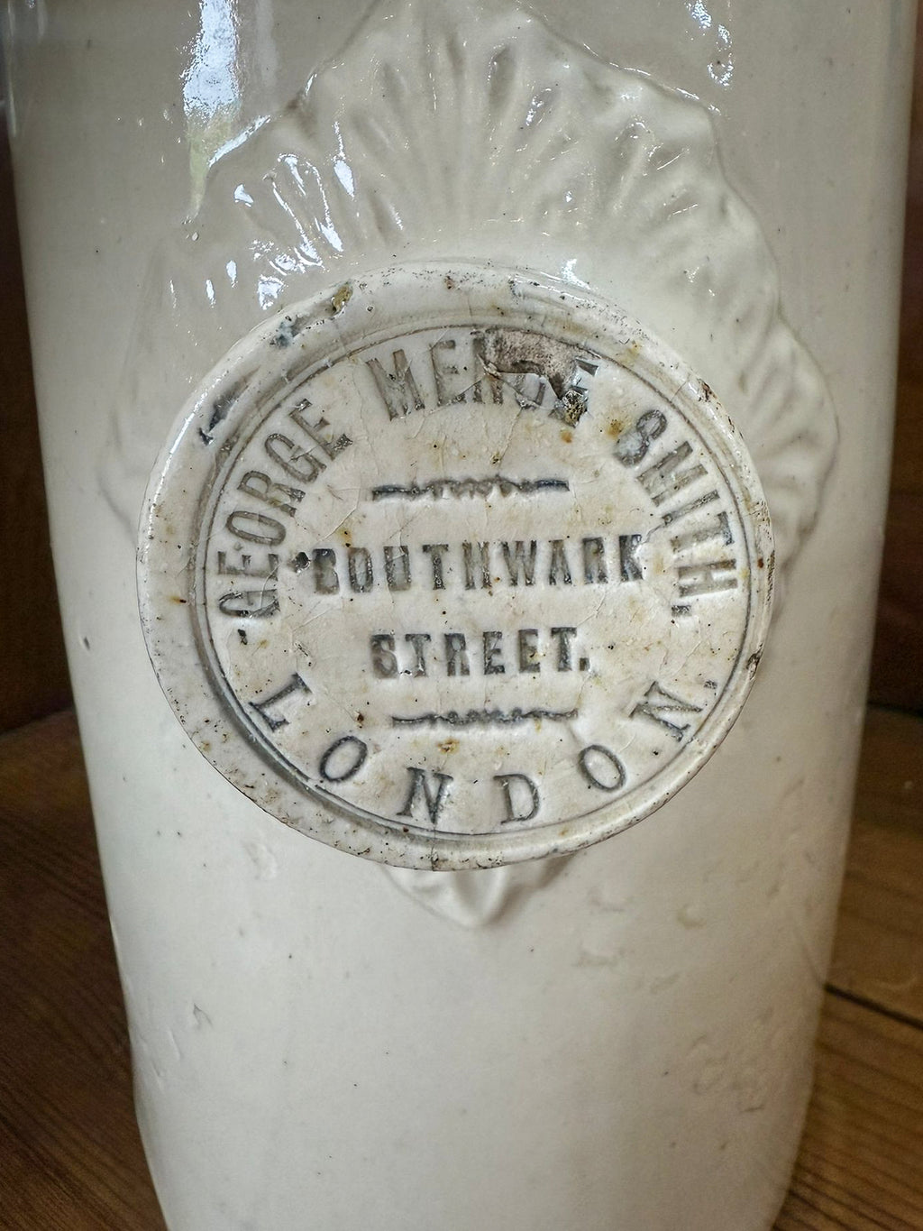 Vintage stoneware hot water bottle with a label on a wooden surface