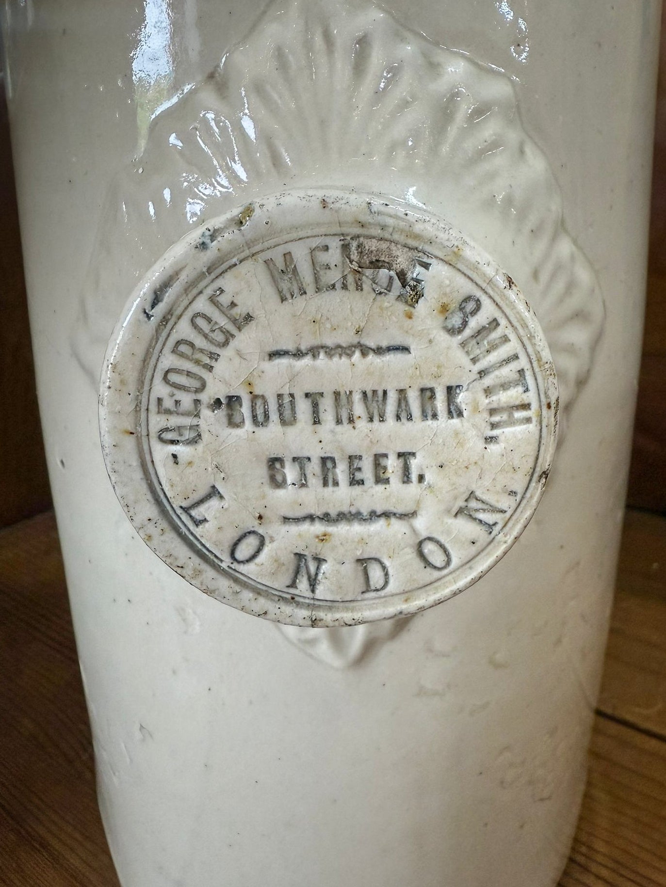 Vintage stoneware hot water bottle with a label on a wooden surface