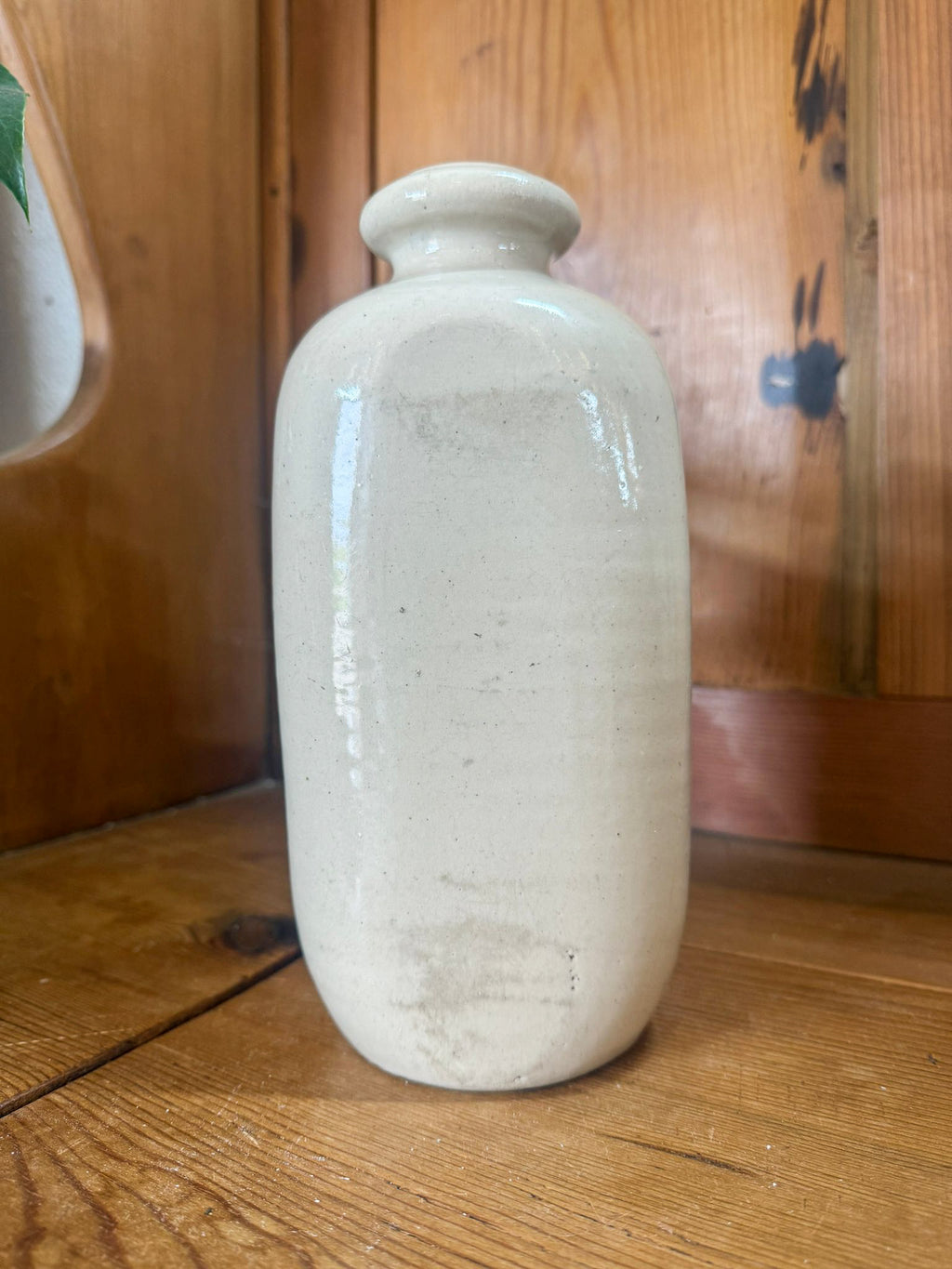 White ceramic hot water bottle on a wooden surface with a wooden cabinet in the background