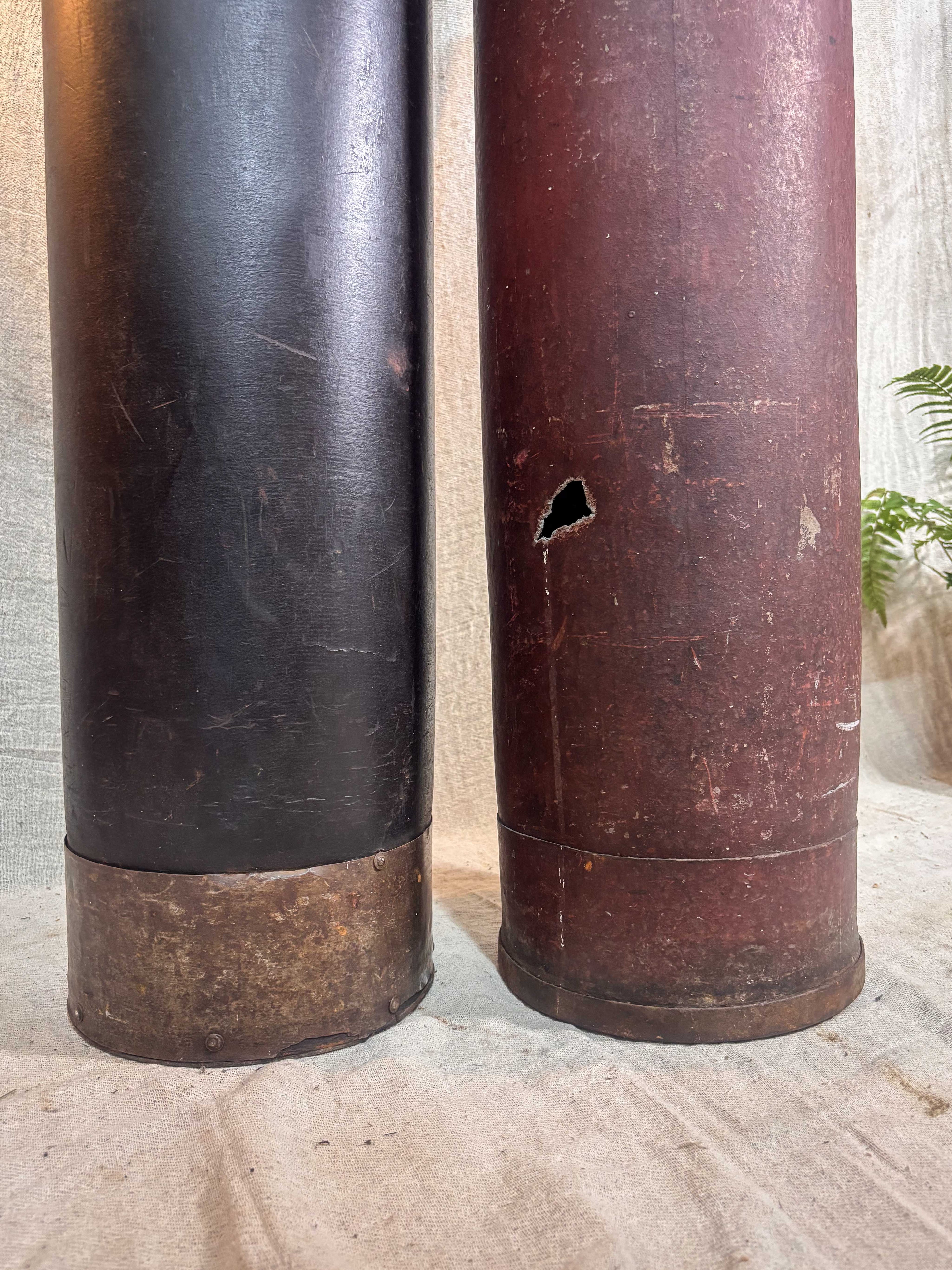 Two cylindrical tubes one black and one brown, on a light-coloured surface.